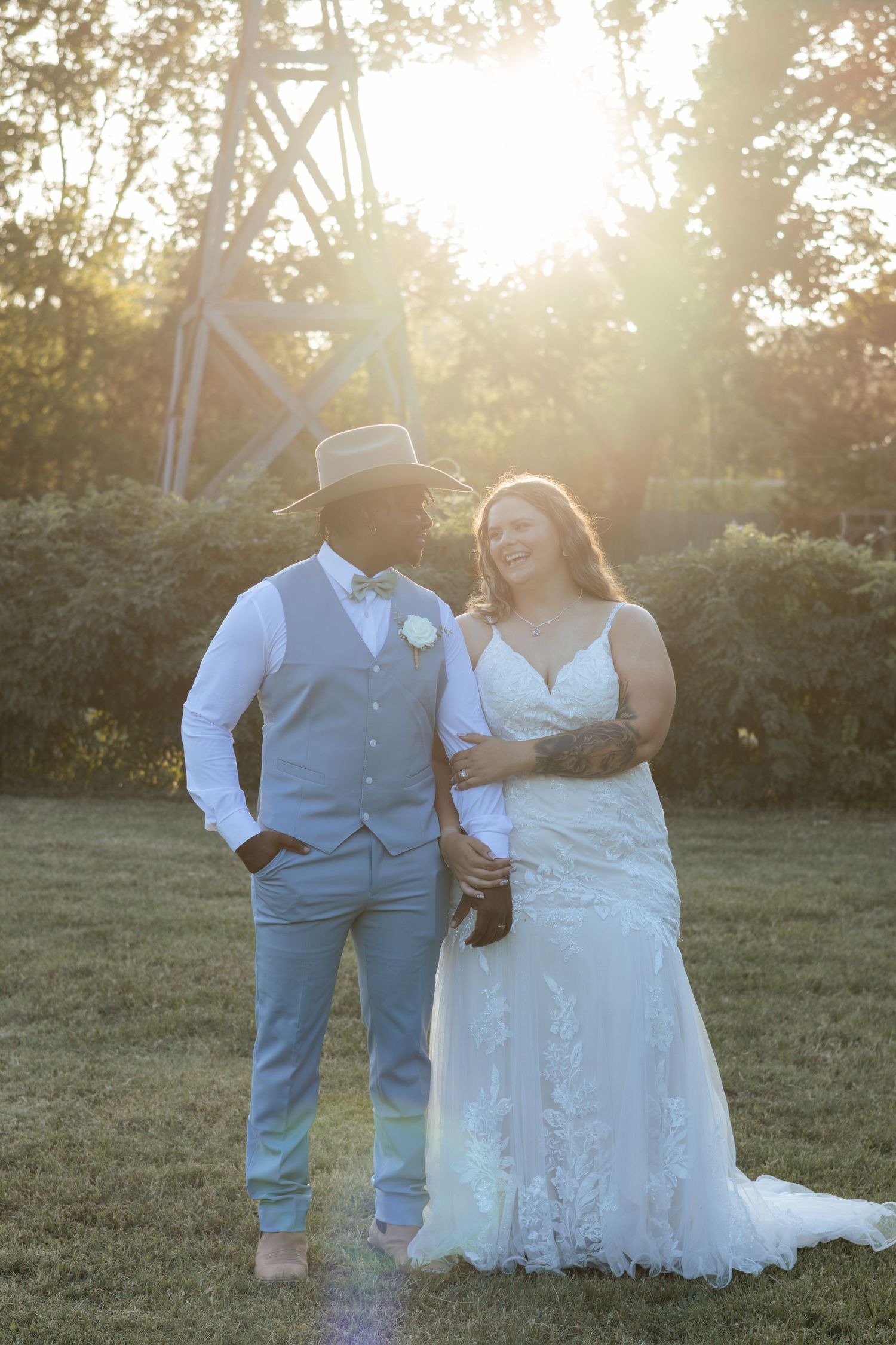 Bride and groom sharing a romantic golden hour moment on lush green grass at sunset.