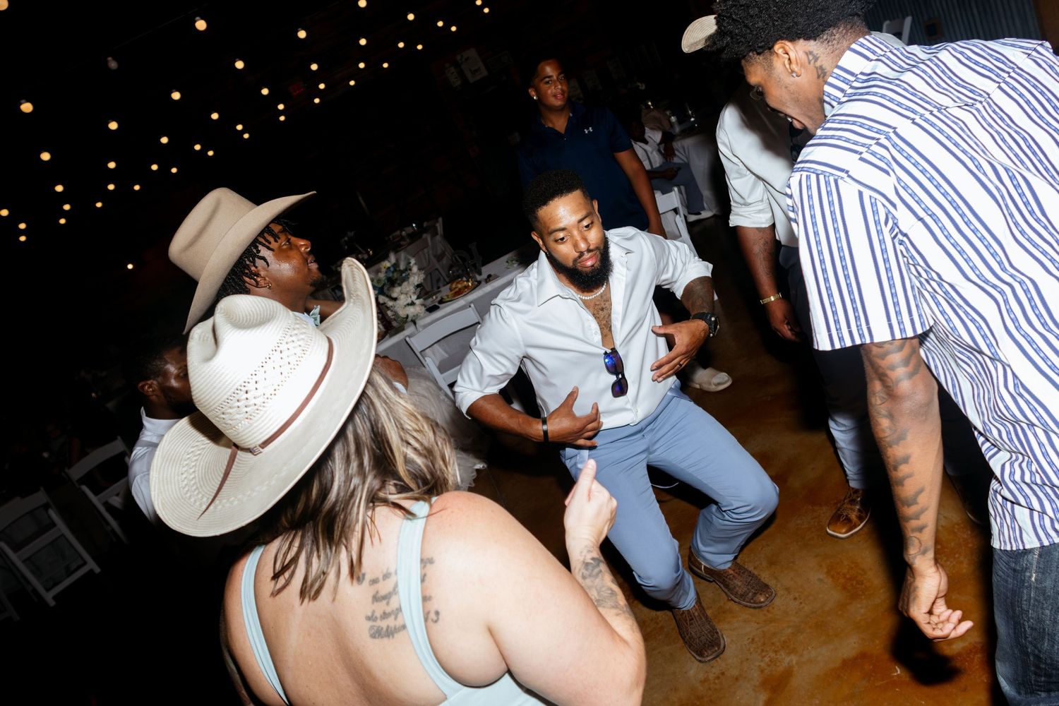 People dancing energetically at an outdoor evening party, with string lights and festive atmosphere.