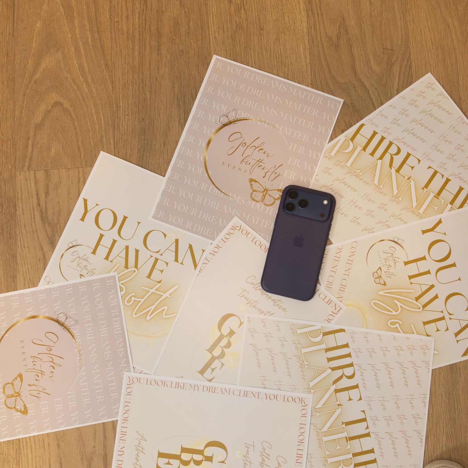 Gold foil motivational cards spread on wooden floor with purple iPhone, featuring phrases like You Can Have It All.
