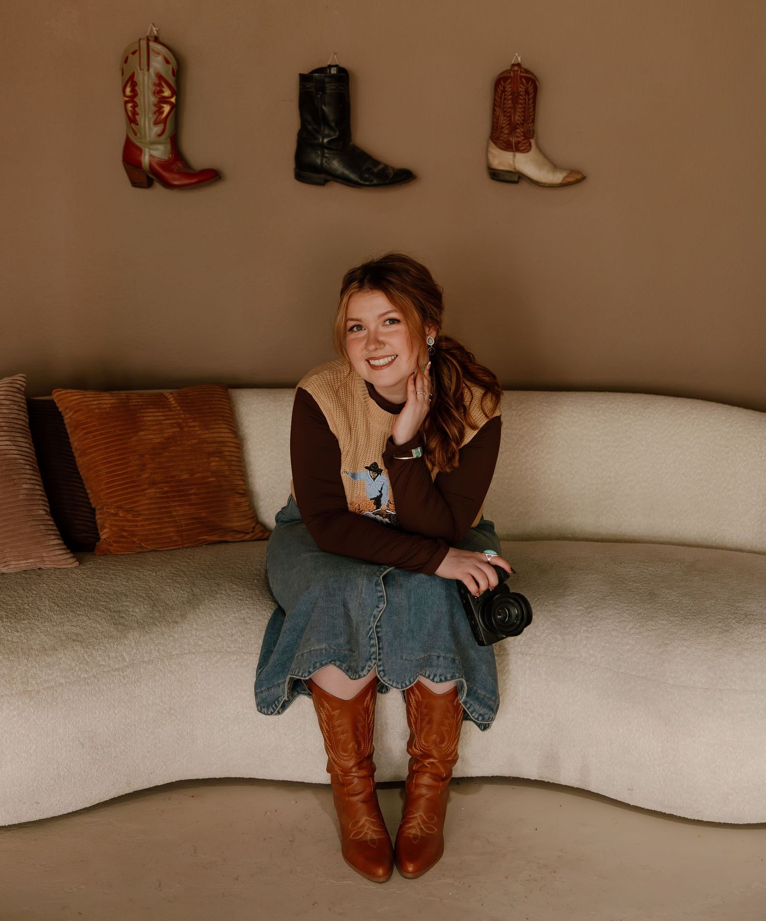 Stylish brown leather boots displayed on wall above cozy seating area with warm aesthetic and decorative pillows.