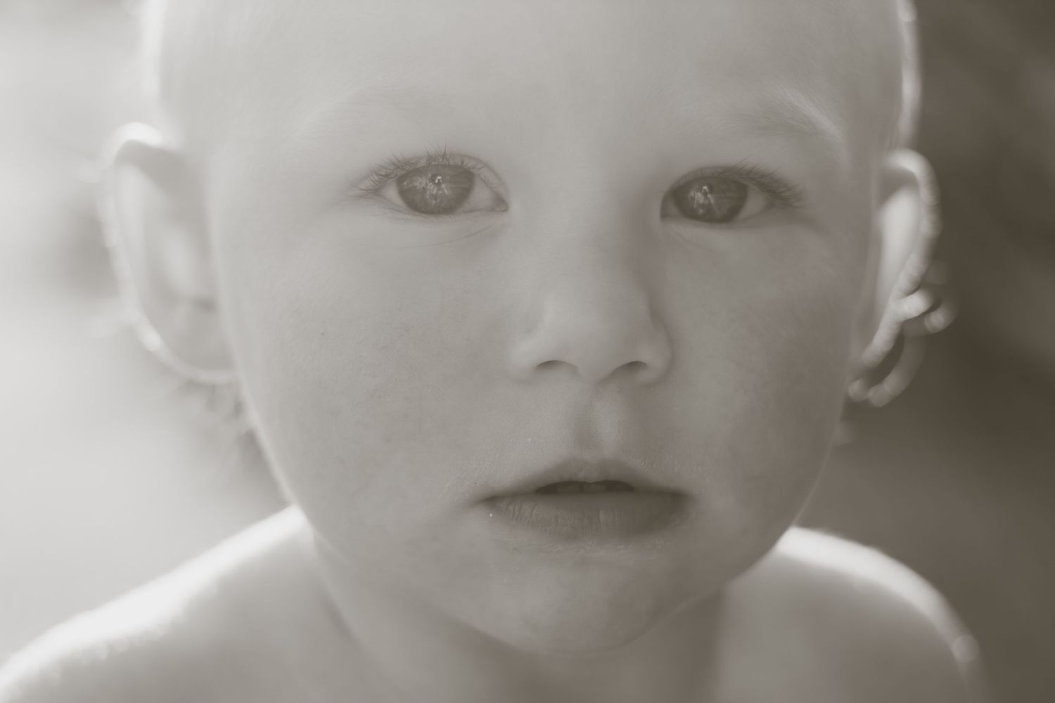 Black and white close-up portrait of a curious baby with soft features and expressive eyes.