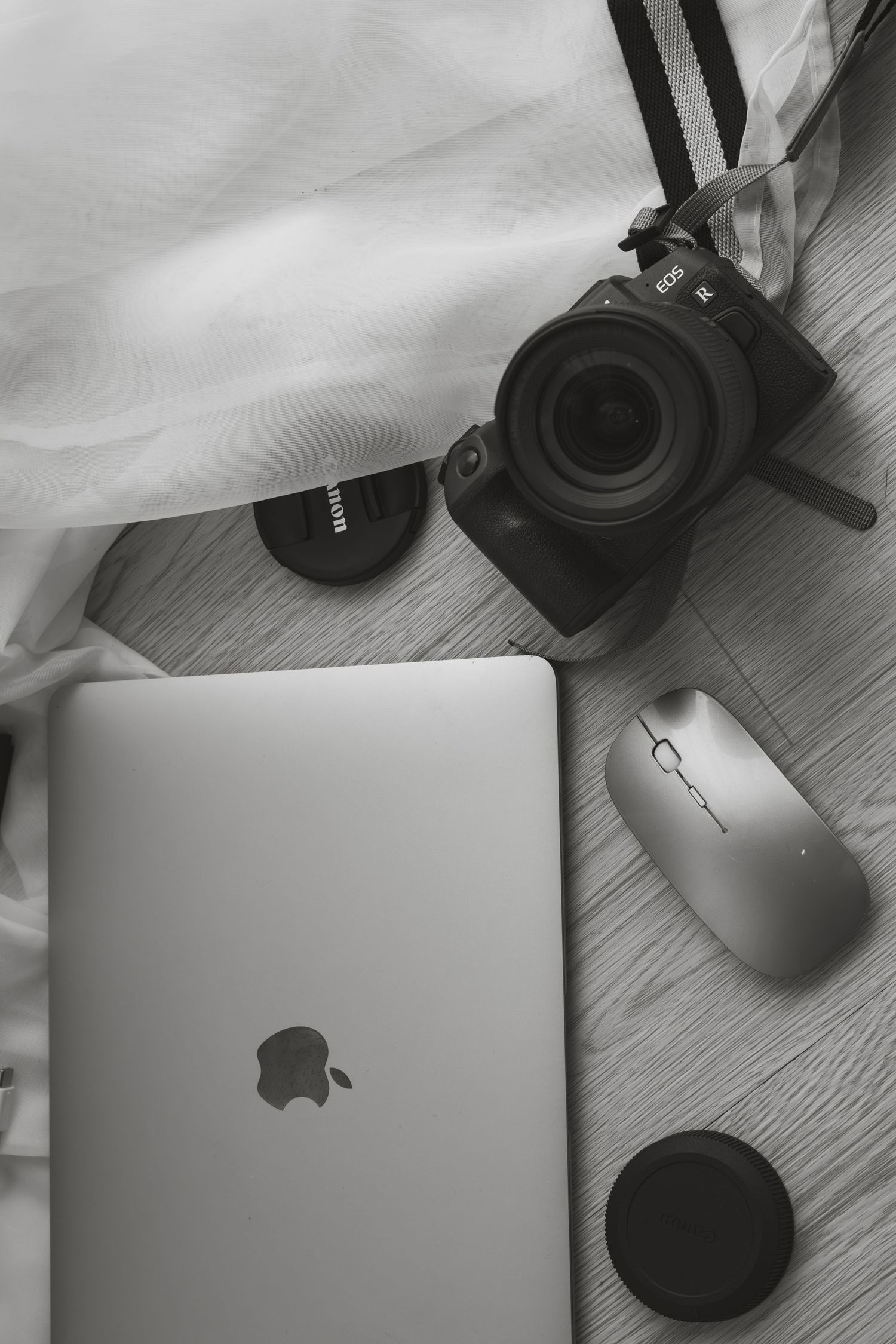 A series of monochromatic images showing a MacBook laptop and wireless mouse from different angles on a light wooden surface.