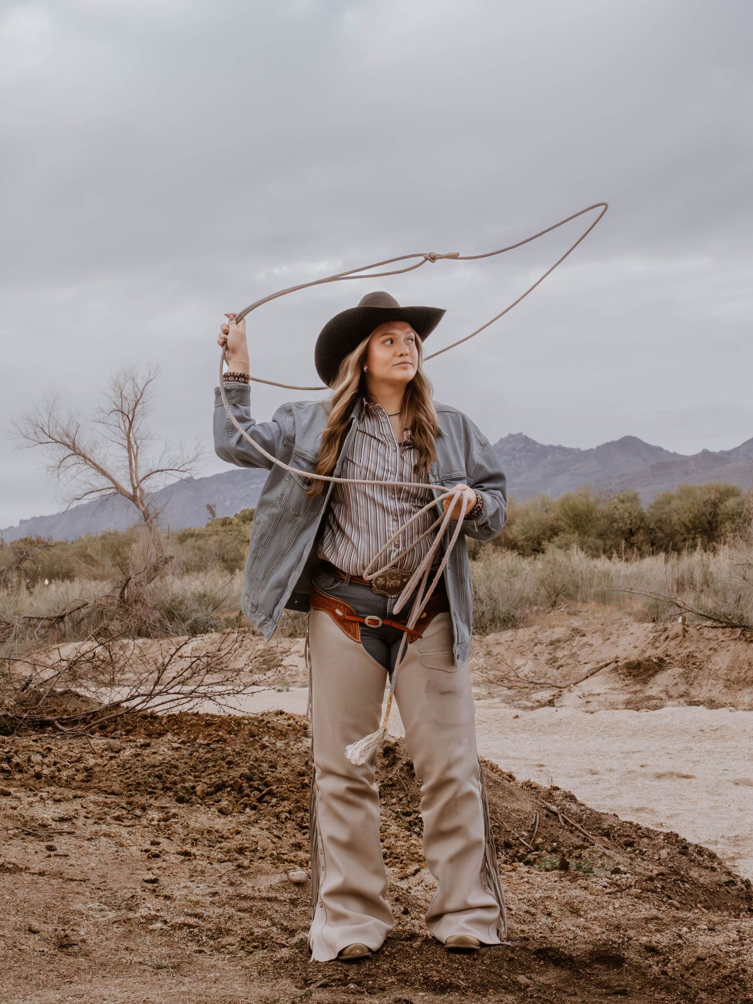 Desert fashion photography with wide-brimmed hat and casual western style clothing.