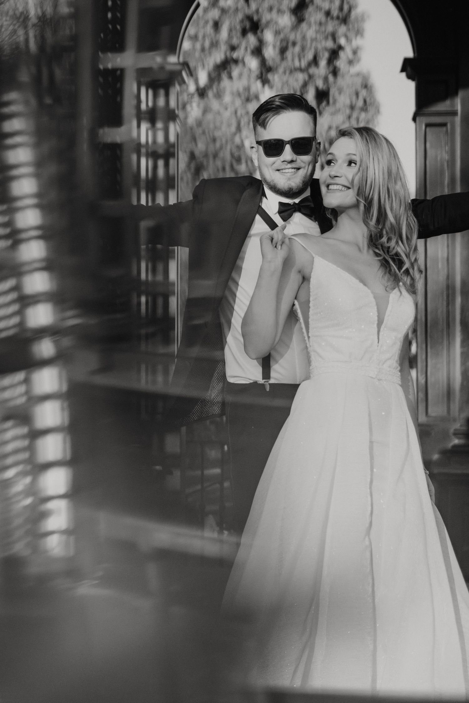 Black and white wedding photo showing a couple in formal attire sharing a romantic moment.