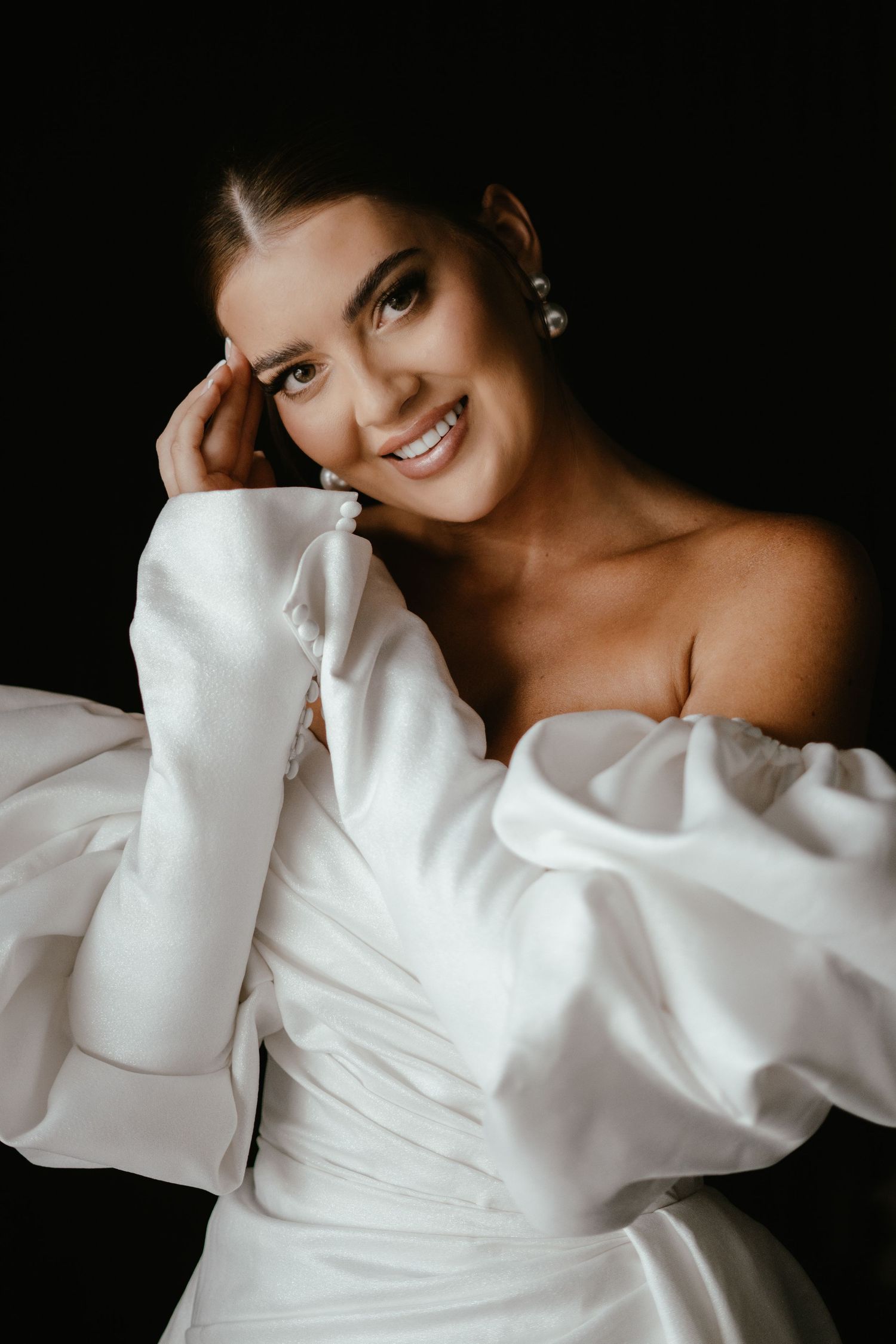 A sequence of artistic portrait shots featuring a white off-shoulder dress against a dark background.