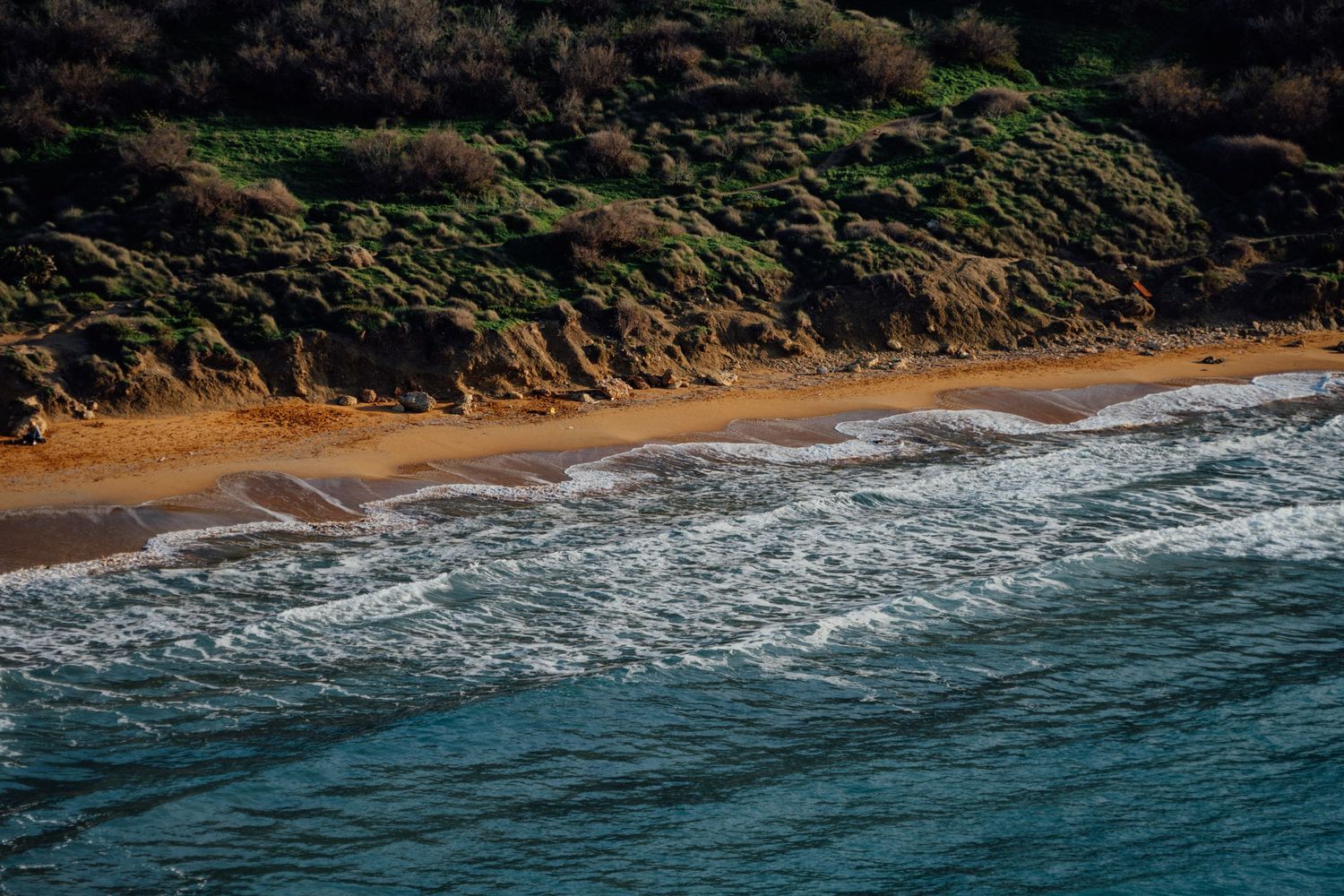 Aerial view of a rugged coastline with sandy beach coves nestled between steep cliffs.