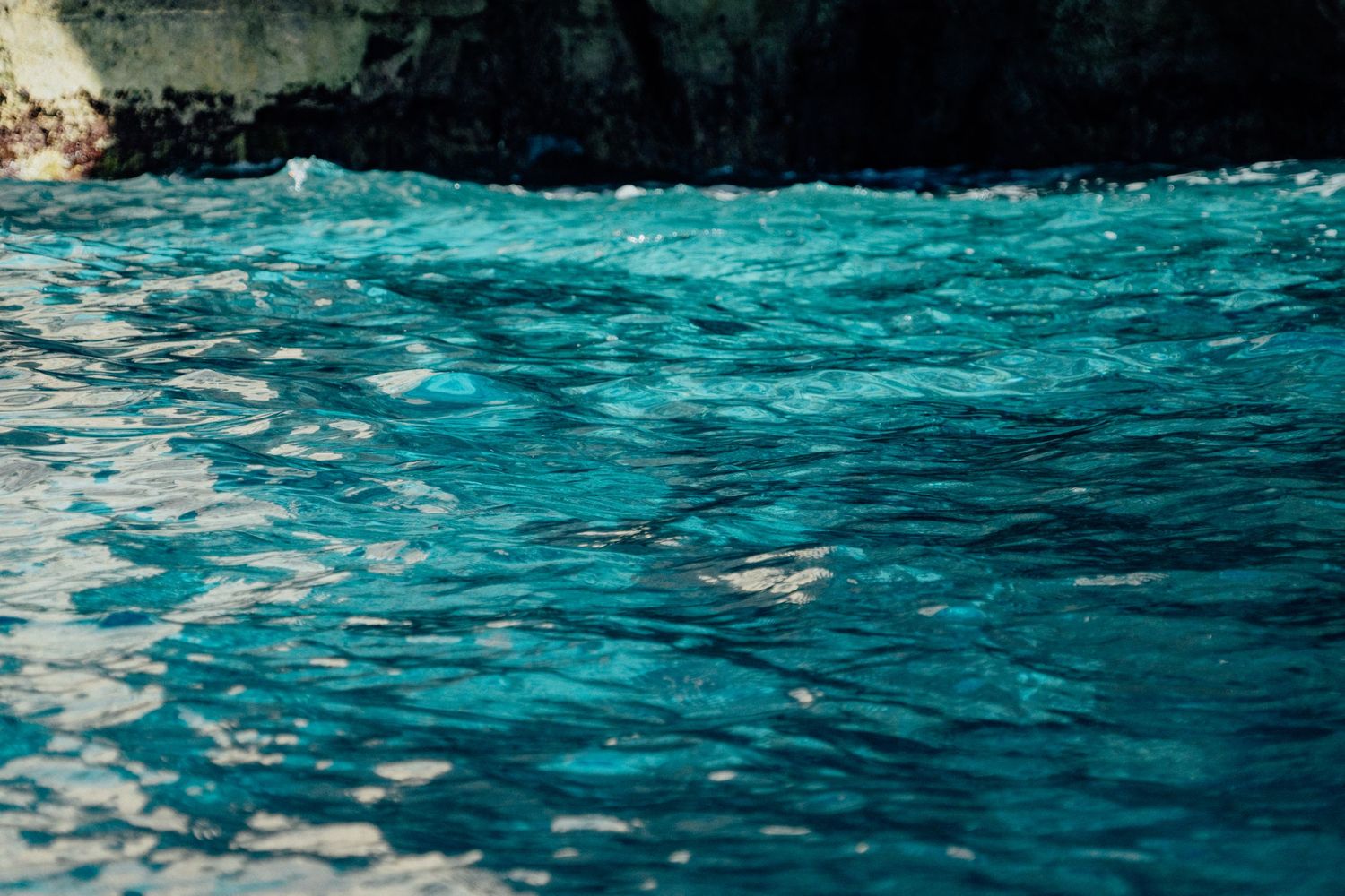 Turquoise ocean waves ripple and sparkle under bright sunlight.