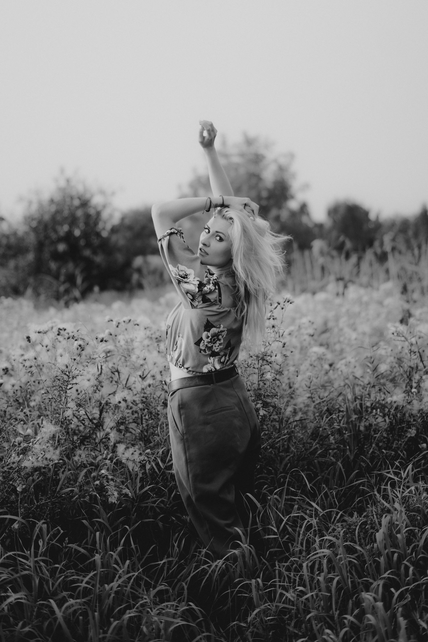 Artistic black and white portraits of someone posing in a wildflower field.