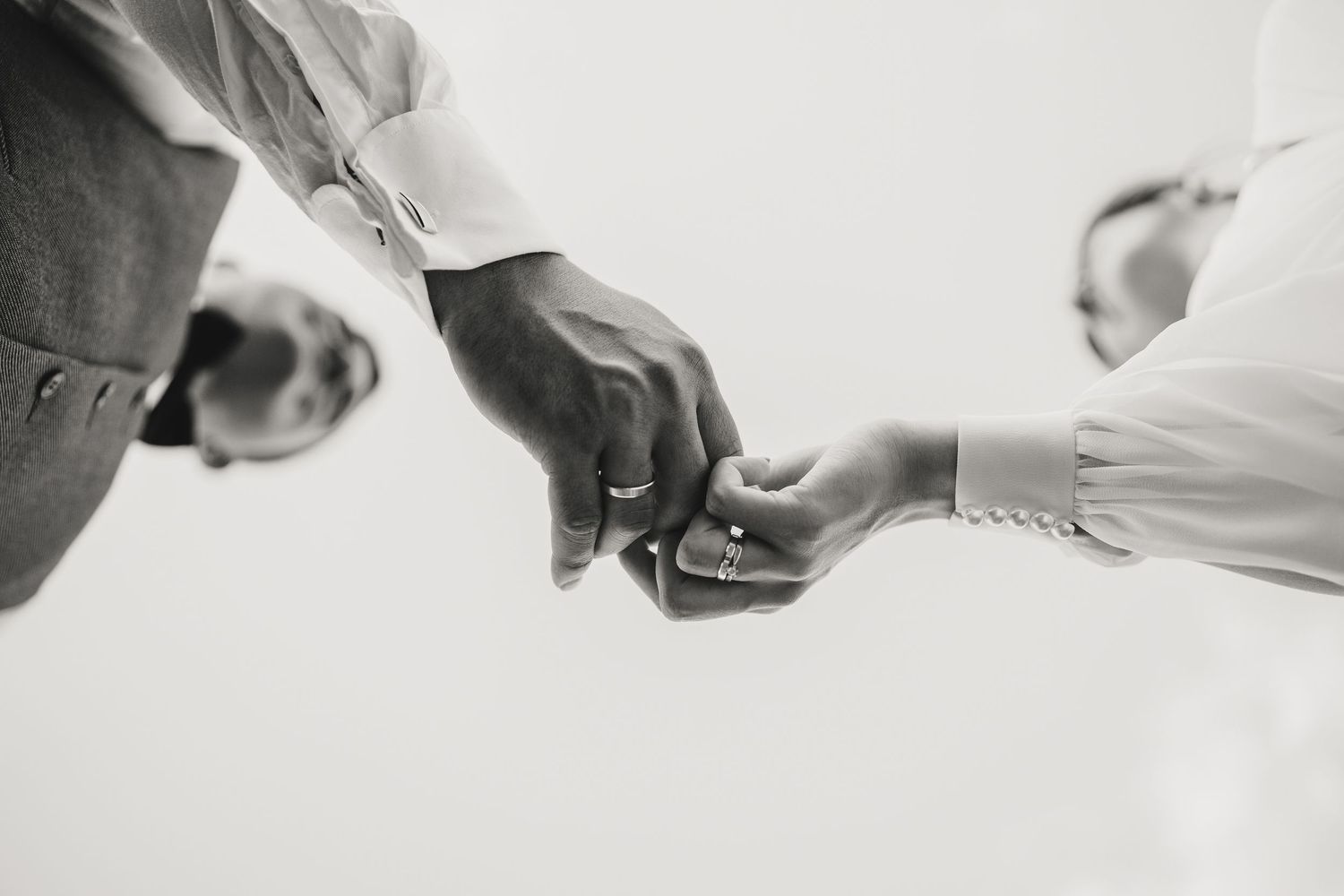 Black and white close-up of hands exchanging wedding rings during ceremony.