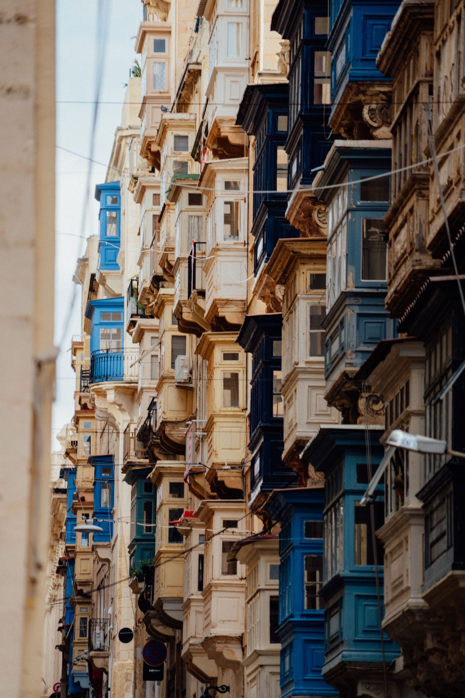 Traditional Maltese architecture featuring colorful wooden balconies on historic limestone buildings.