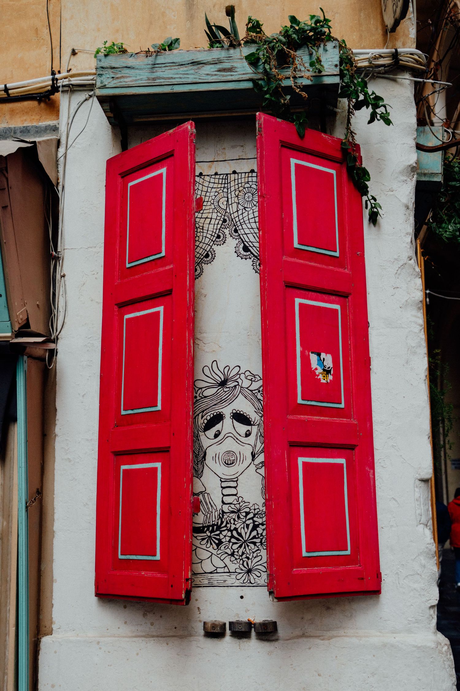 Charming white wall with bright red shuttered windows and decorative details.