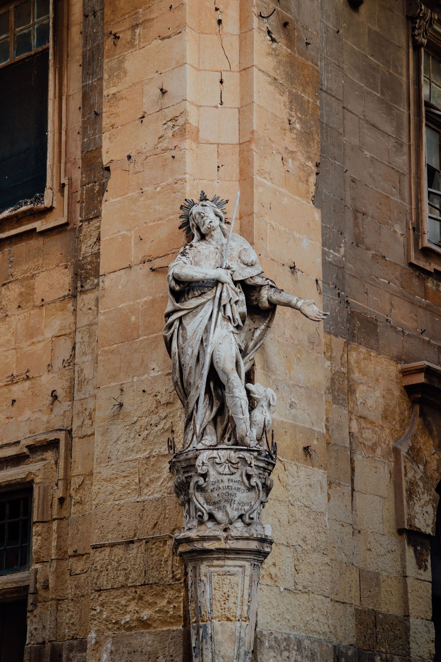 Classical stone statues adorning the corner of a historic limestone building.