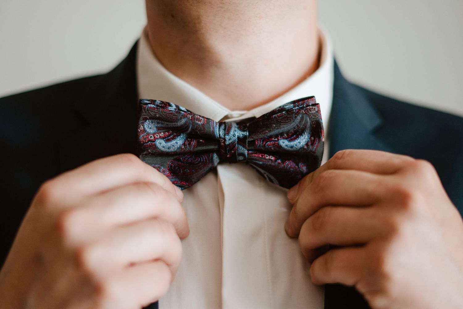 Close-up shots of hands adjusting a patterned bow tie.