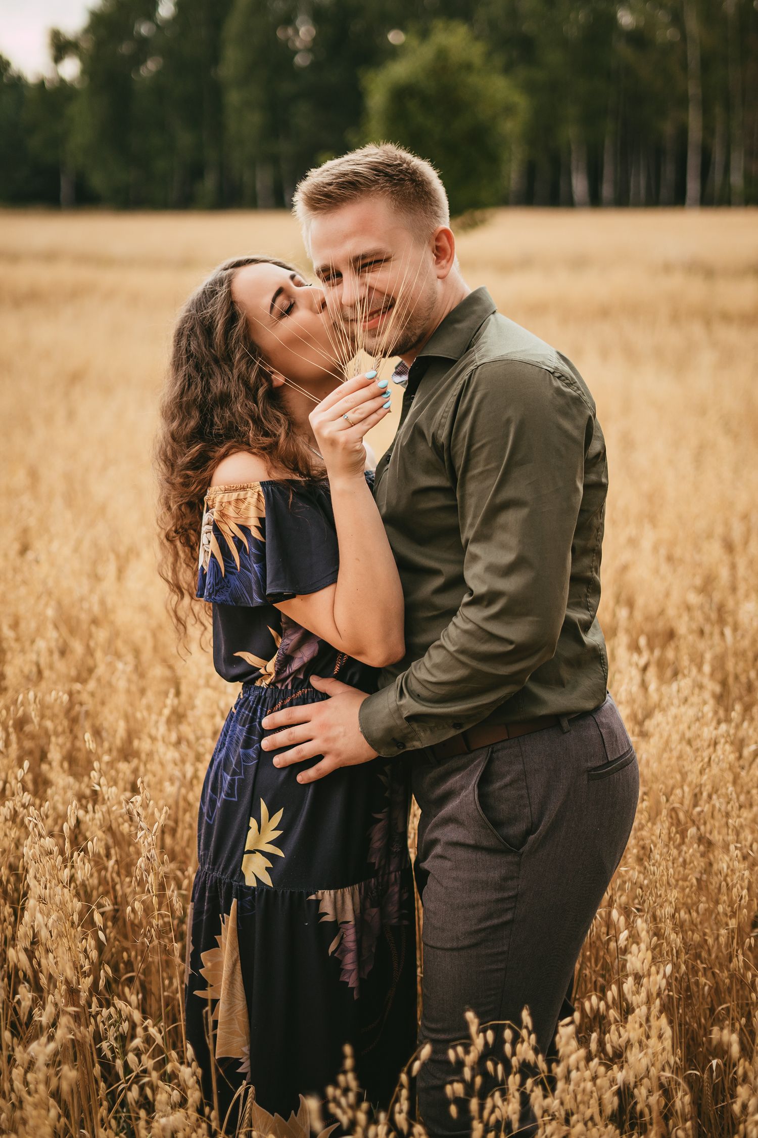 A romantic couple embraces in a golden wheat field during sunset creating an intimate moment in nature.