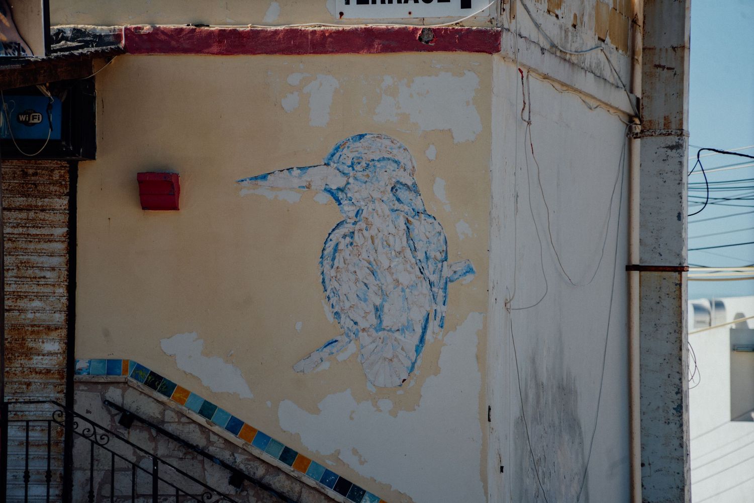 Weathered wall with faded blue graffiti art in an urban setting.