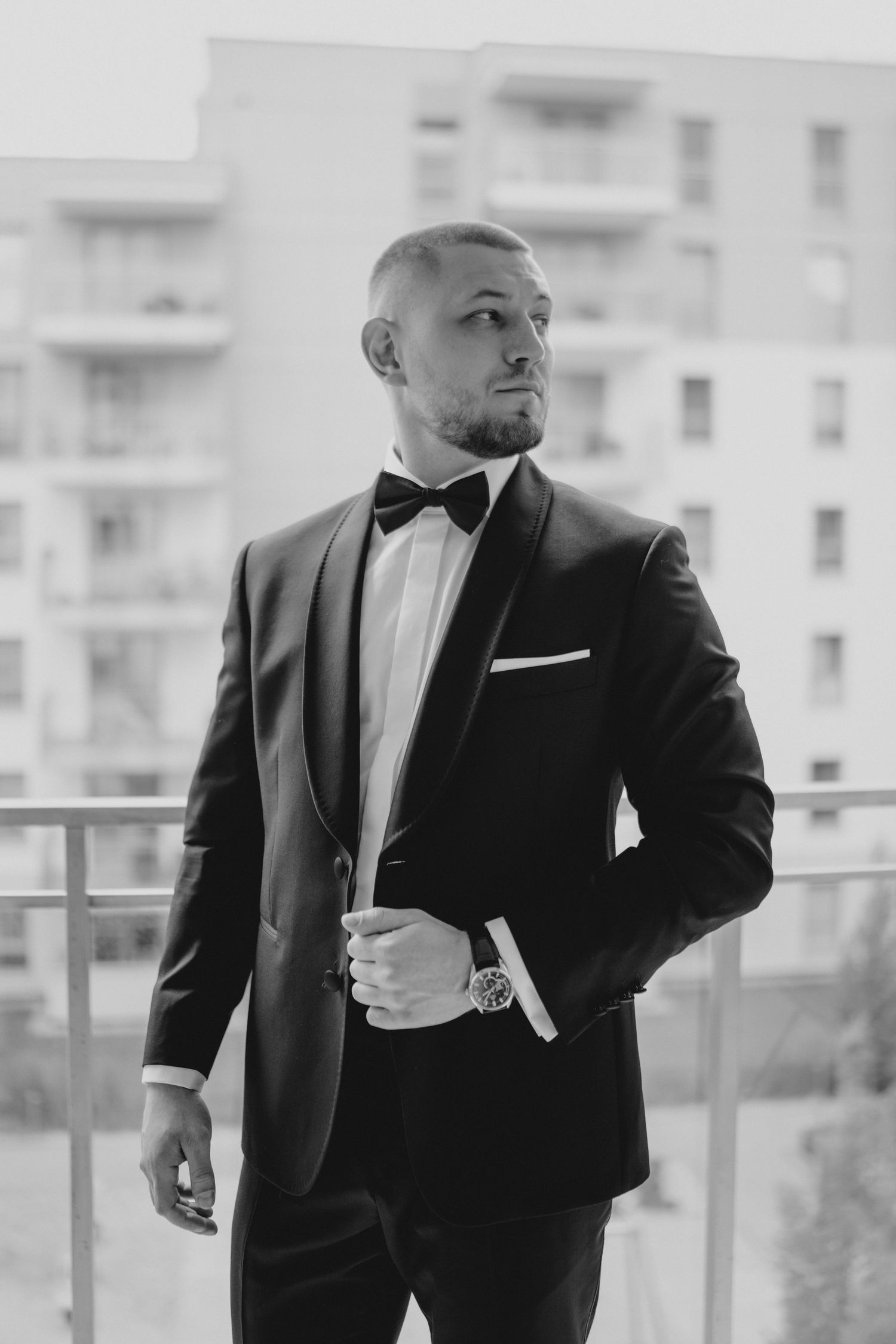 Black and white photo series of a man in a formal tuxedo posing against a bright window background.