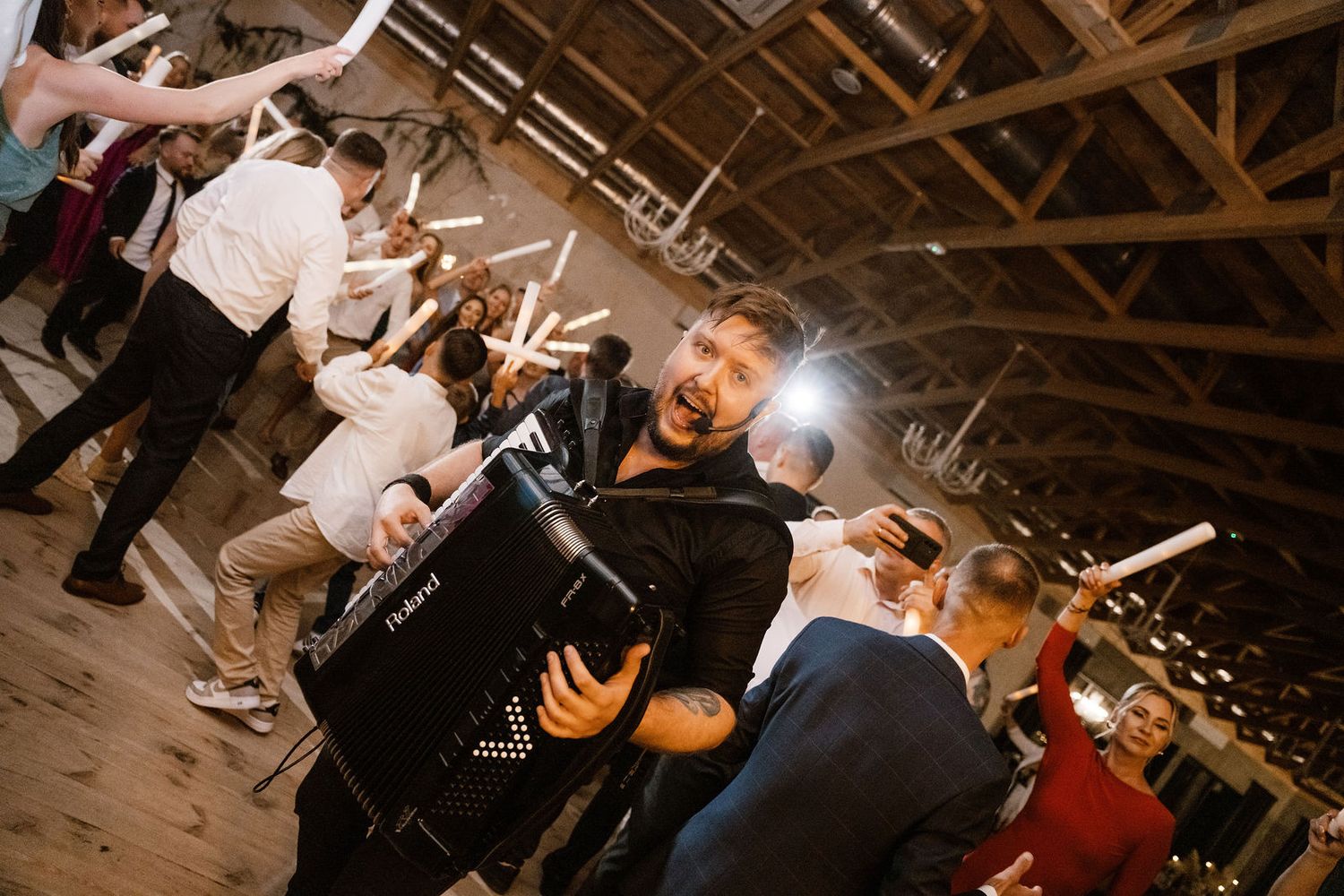 Wedding guests dance and celebrate on a rustic wooden dance floor during an evening reception.