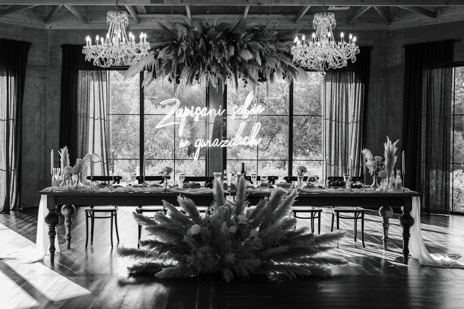 Panoramic view of an elegant restaurant interior with crystal chandeliers and modern decor in black and white tones.