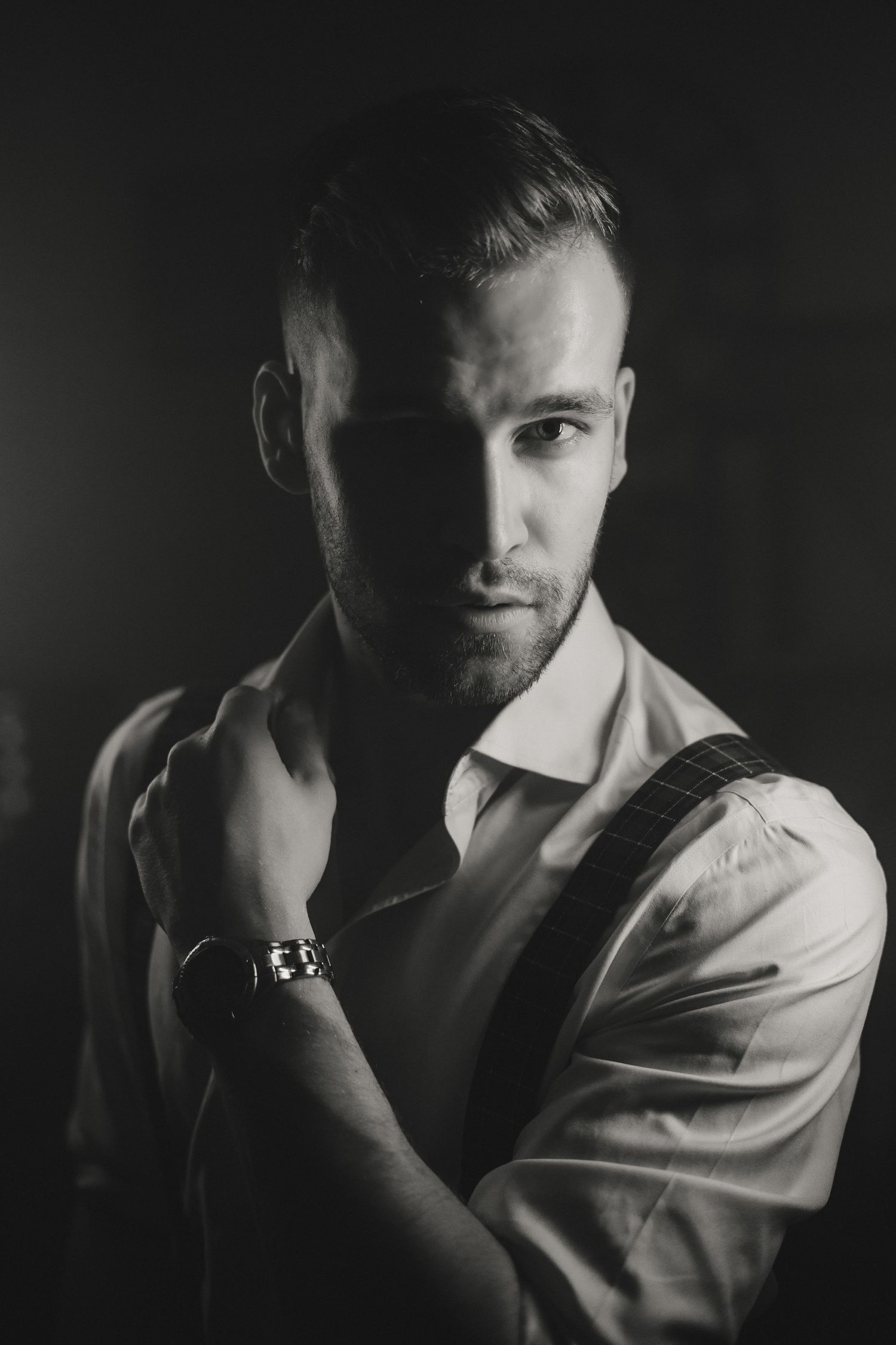 Dramatic black and white portrait with moody lighting and shadows.