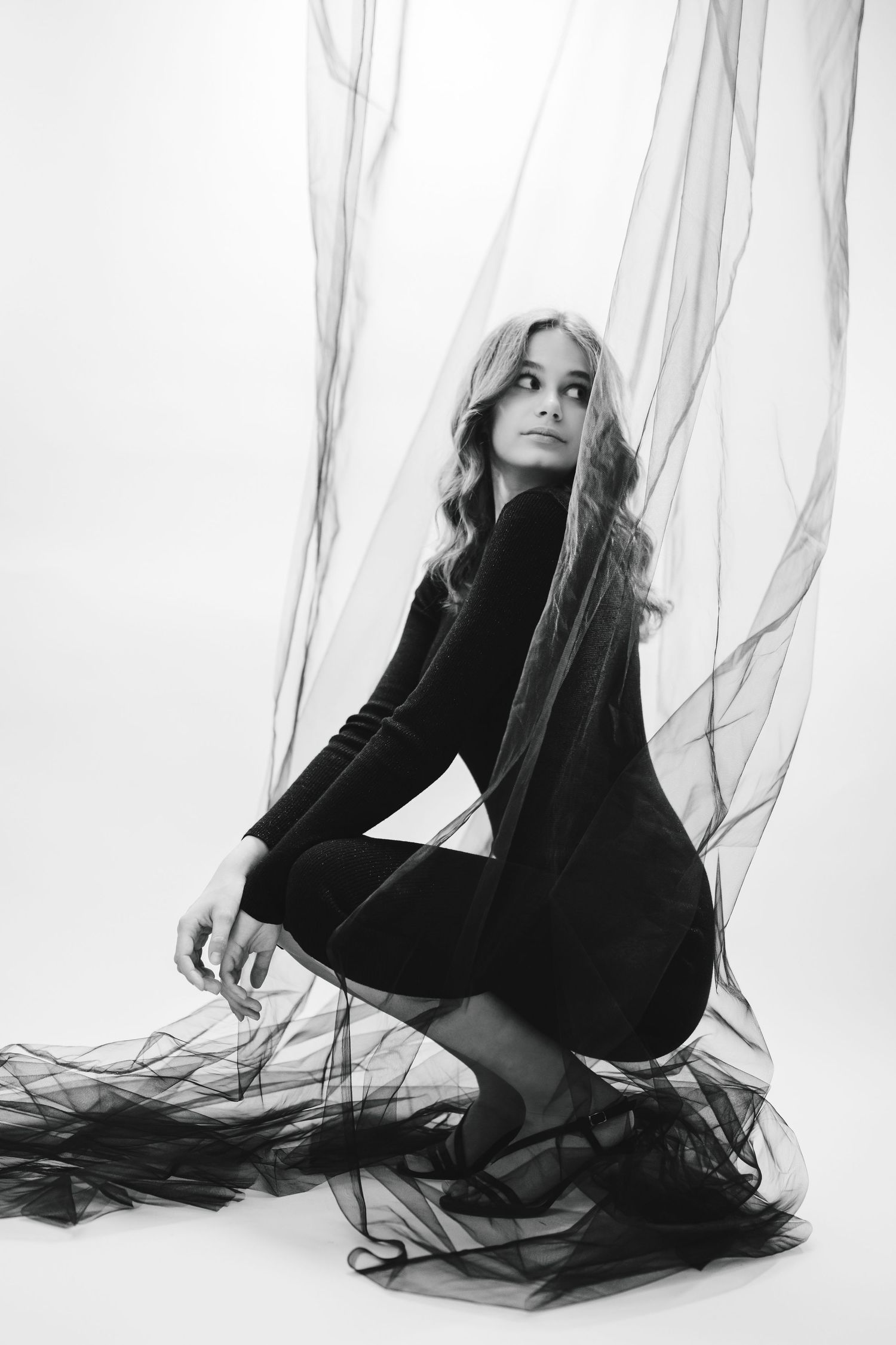 Dramatic black and white fashion portrait with flowing sheer fabric.