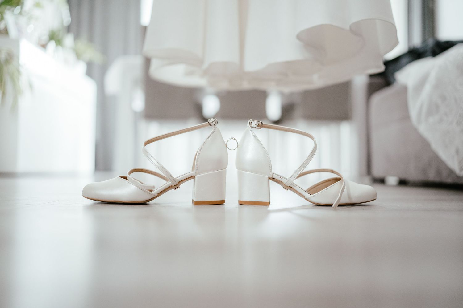 Elegant white bridal sandals with block heels arranged on a light surface.