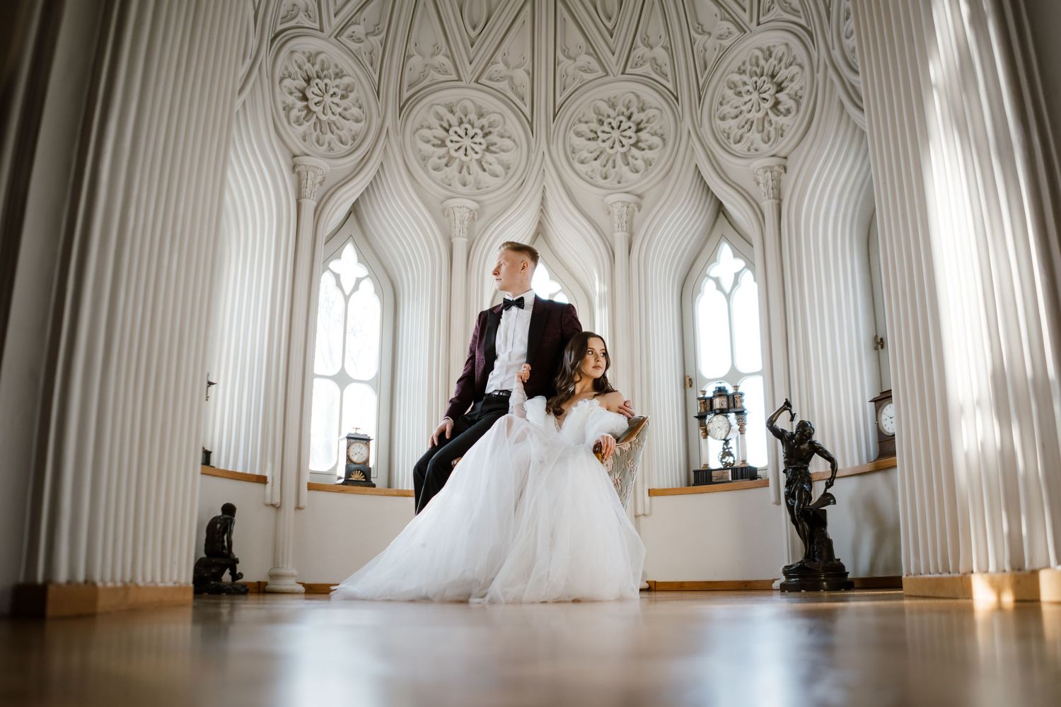 Wedding couple photographed in panoramic series inside ornate white Gothic cathedral hall.