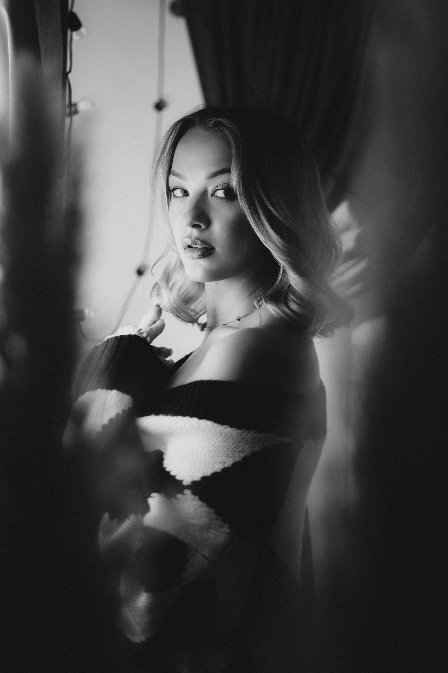 Black and white portrait of a blonde woman in a strapless top, gazing at camera with soft dramatic lighting.