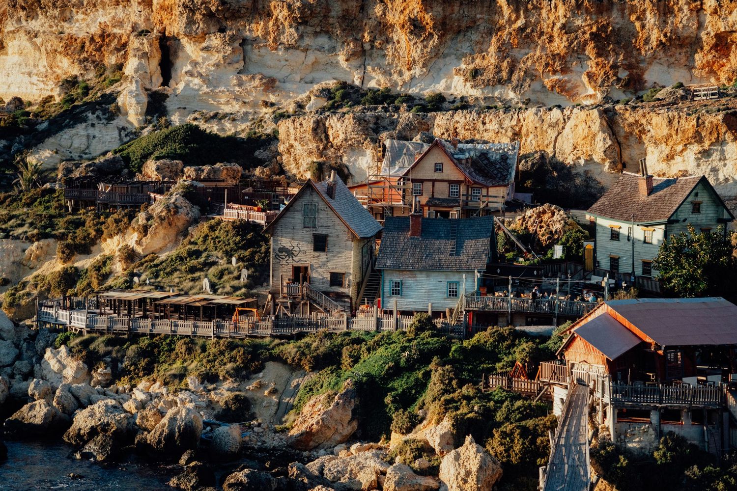 Coastal houses and buildings nestled along rocky cliffs at sunset.