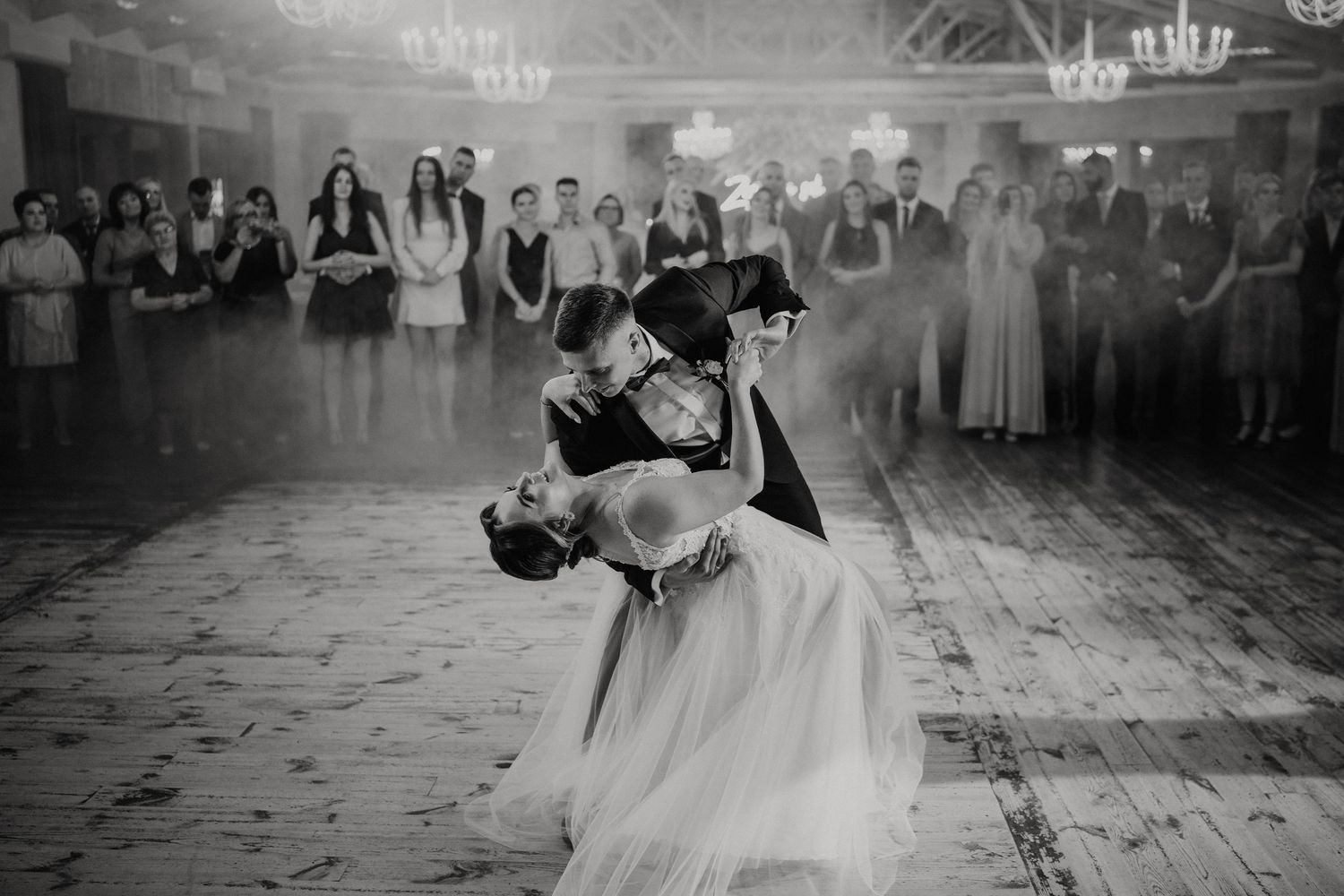 A series of black and white wedding reception photos showing dancing and celebration moments on a rustic wooden floor.