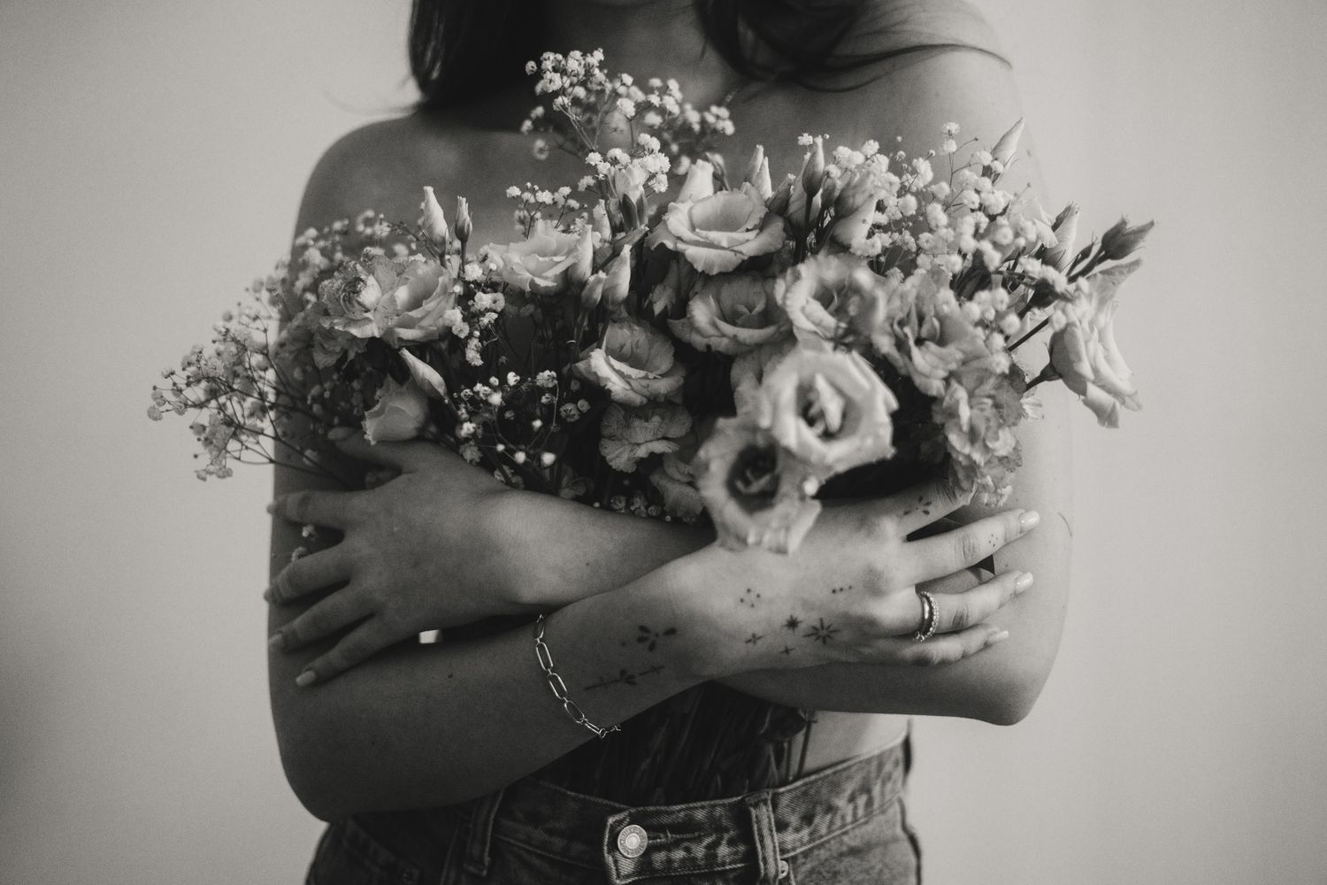 Monochrome image of a person holding a romantic bouquet of flowers against a light background.