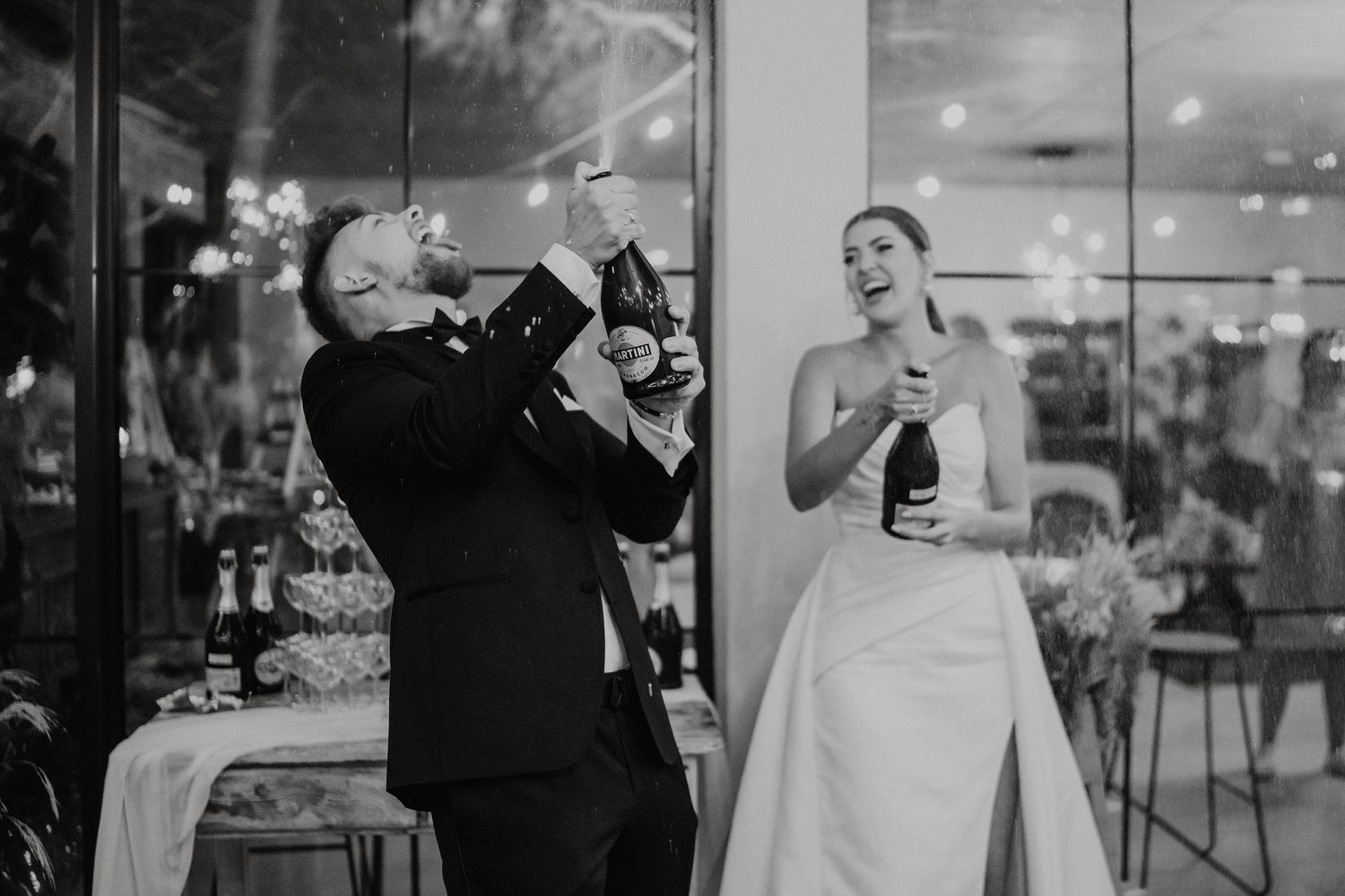 A black and white photo of two people at a wedding reception sharing a celebratory drink together.