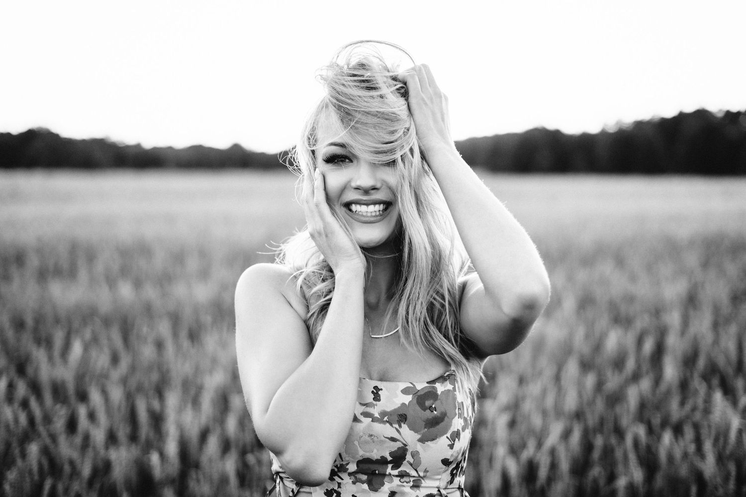Black and white candid portrait showing joyful expression in a wheat field.