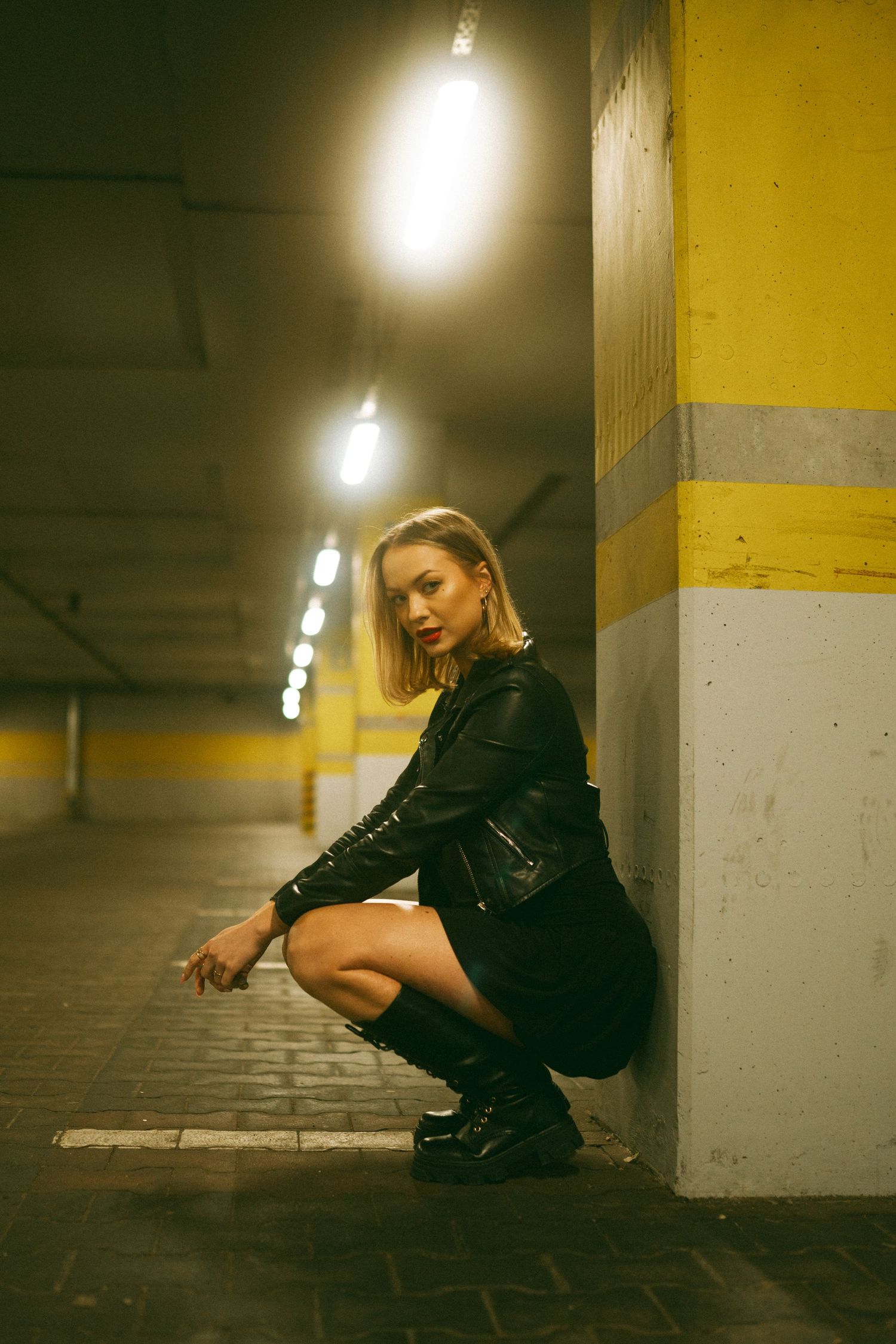Moody portrait in an underground parking garage with dramatic lighting and yellow walls.