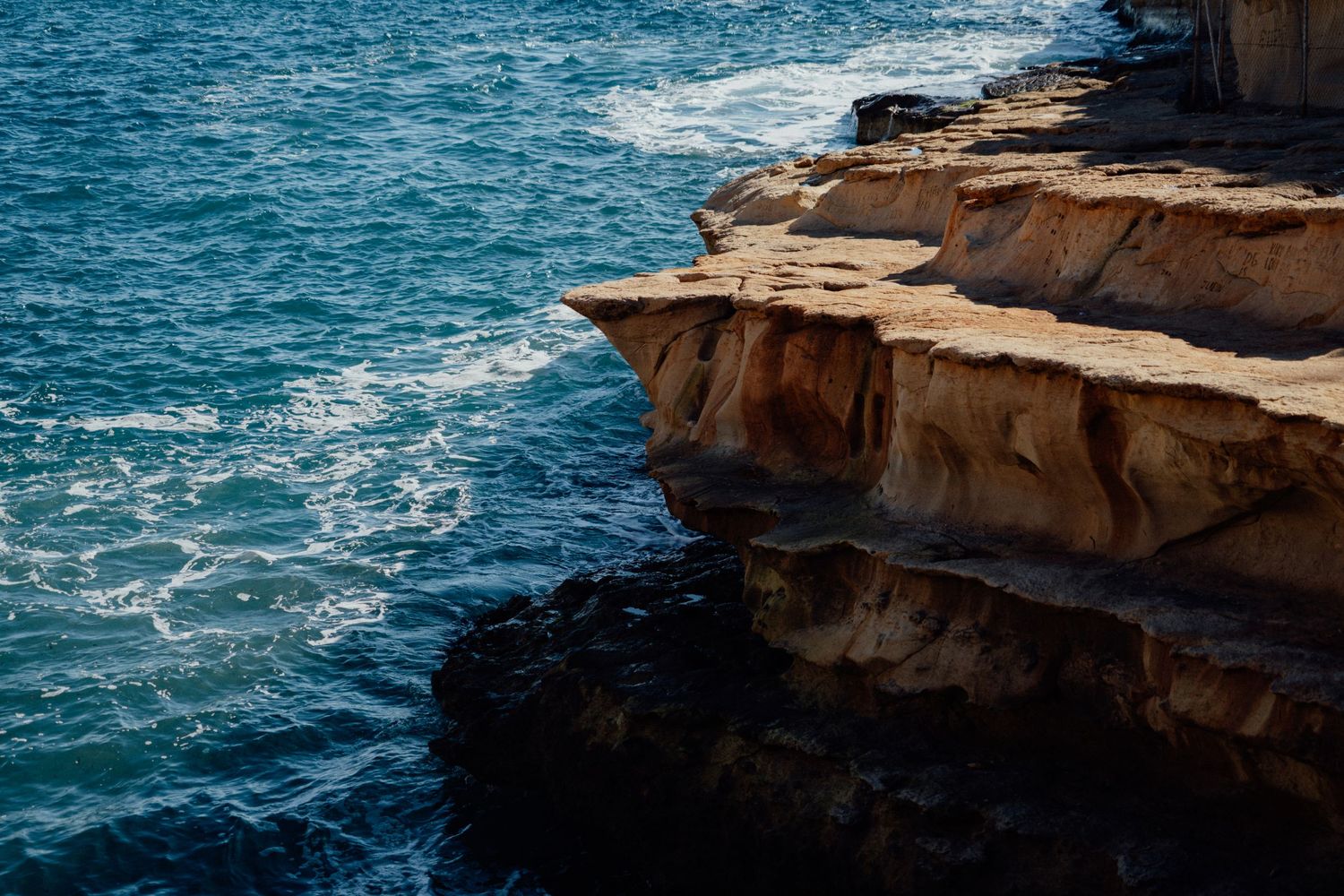 Rugged coastal cliffs meet turquoise Mediterranean waters along a rocky shoreline.