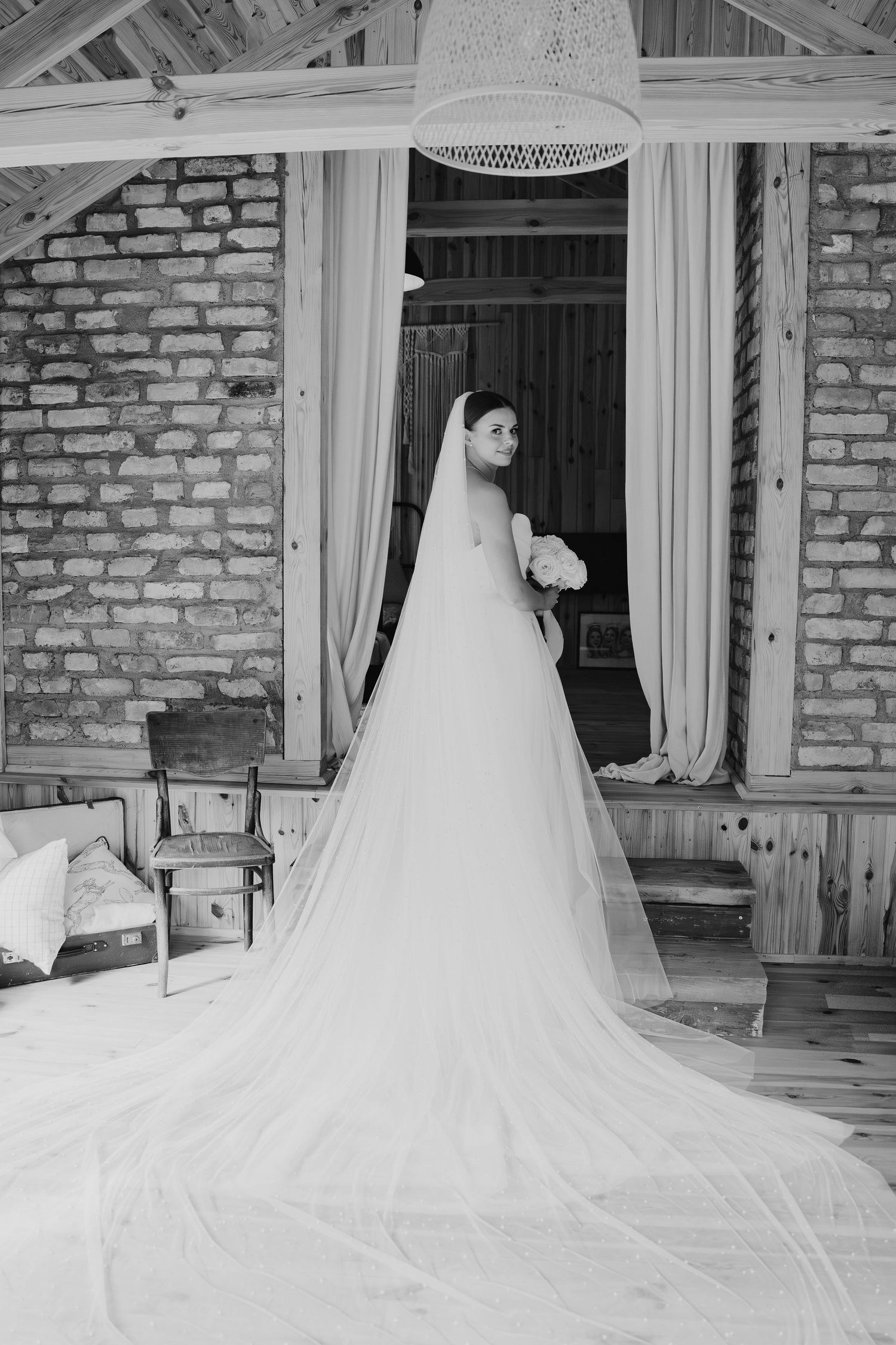 A stunning wedding dress with long train photographed in a rustic brick venue.