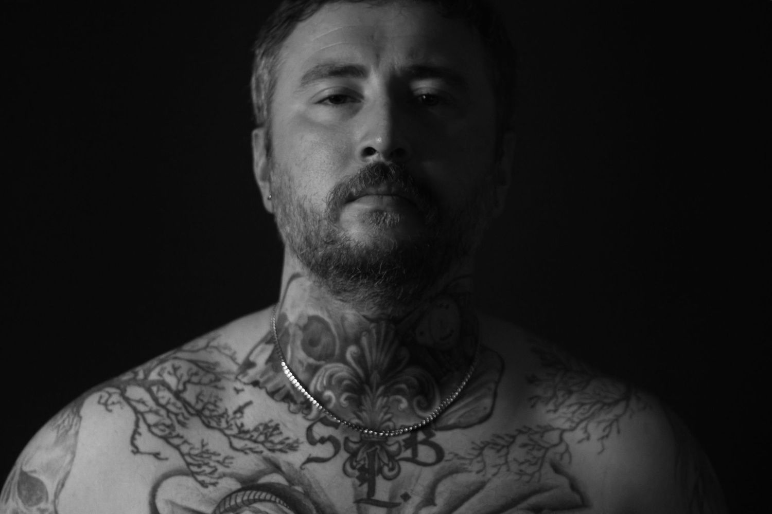 Moody black and white portrait of a tattooed male subject photographed at Hollow Road Studio in Columbia, Missouri.