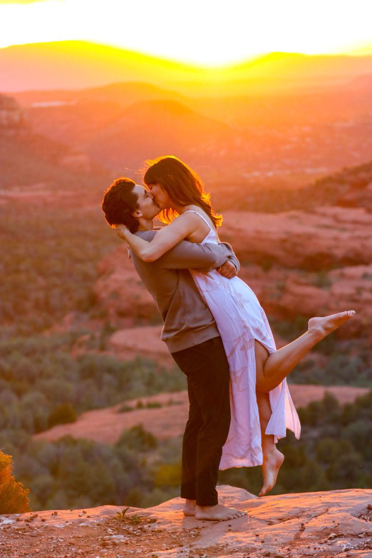 Romantic sunset moment shared between couple on desert cliff overlook in Sedona Arizona.