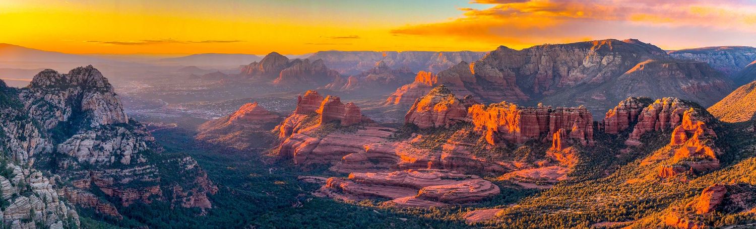 Panoramic sunset view of red rock formations and mountains in Sedona.