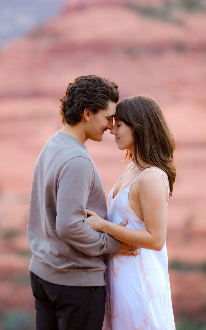 A romantic couple shares an intimate moment against red rock formations at sunset in Sedona Arizona.