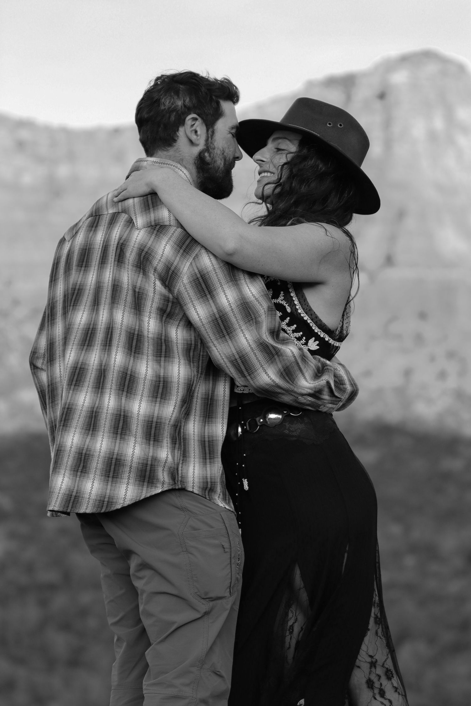 Black and white photo sequence showing a couple embracing and dancing together in a romantic outdoor setting.