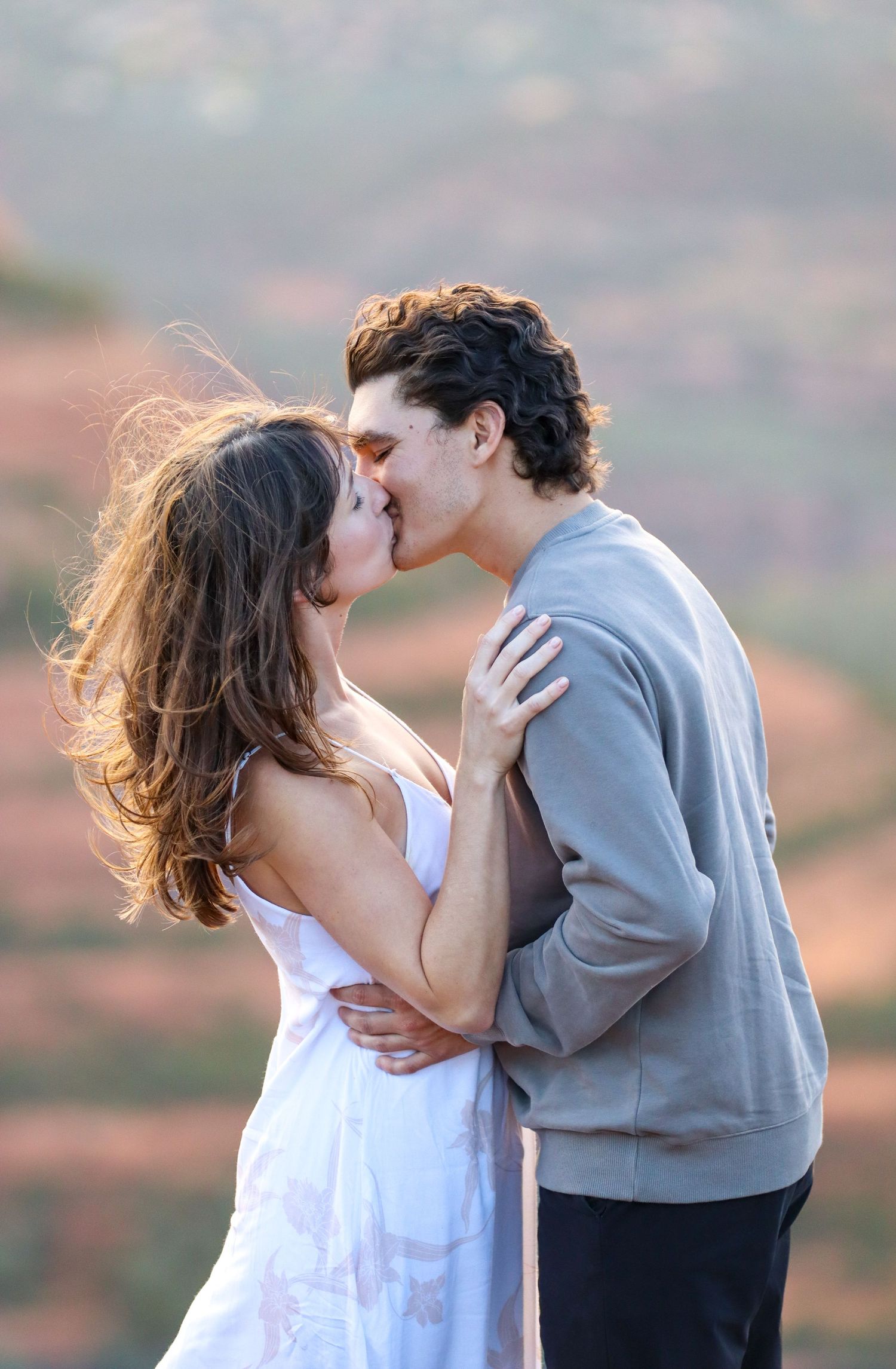 A romantic embrace captured against the backdrop of scenic red rock cliffs in Sedona Arizona.