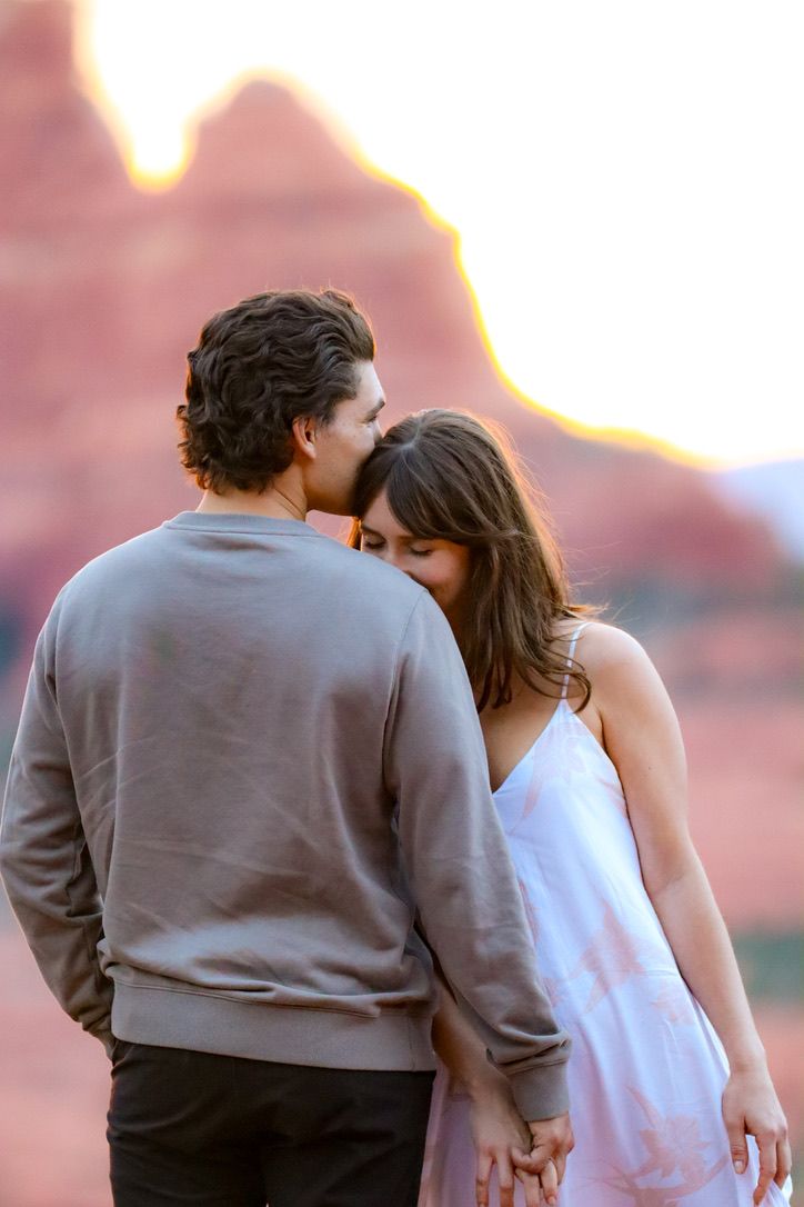 Couple in casual attire sharing an intimate moment against desert mountains in Sedona Arizona.