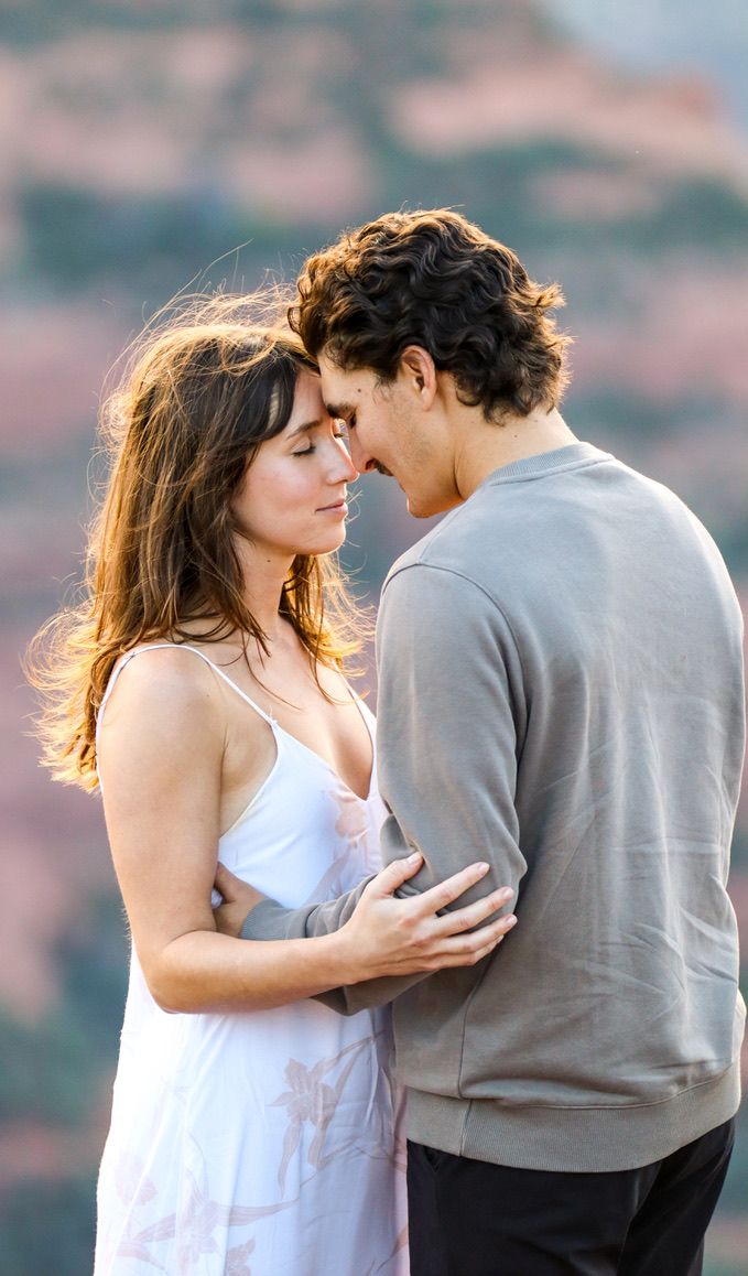 An intimate portrait of a couple in white and grey clothing against a desert landscape.
