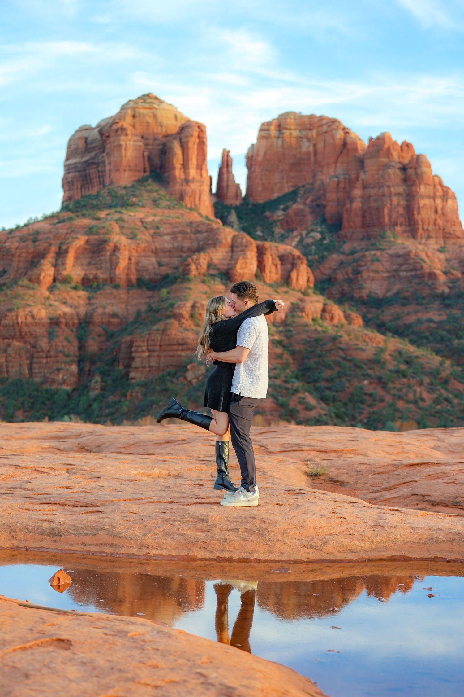 A couple creates reflection photos in a puddle with majestic red rock formations in the background in Sedona Arizona.