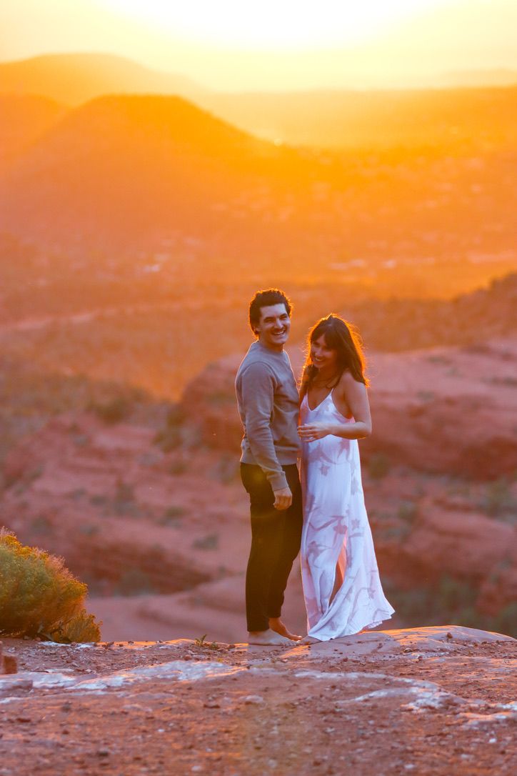 A romantic couple embraces on red rocks during golden hour sunset in Sedona Arizona.