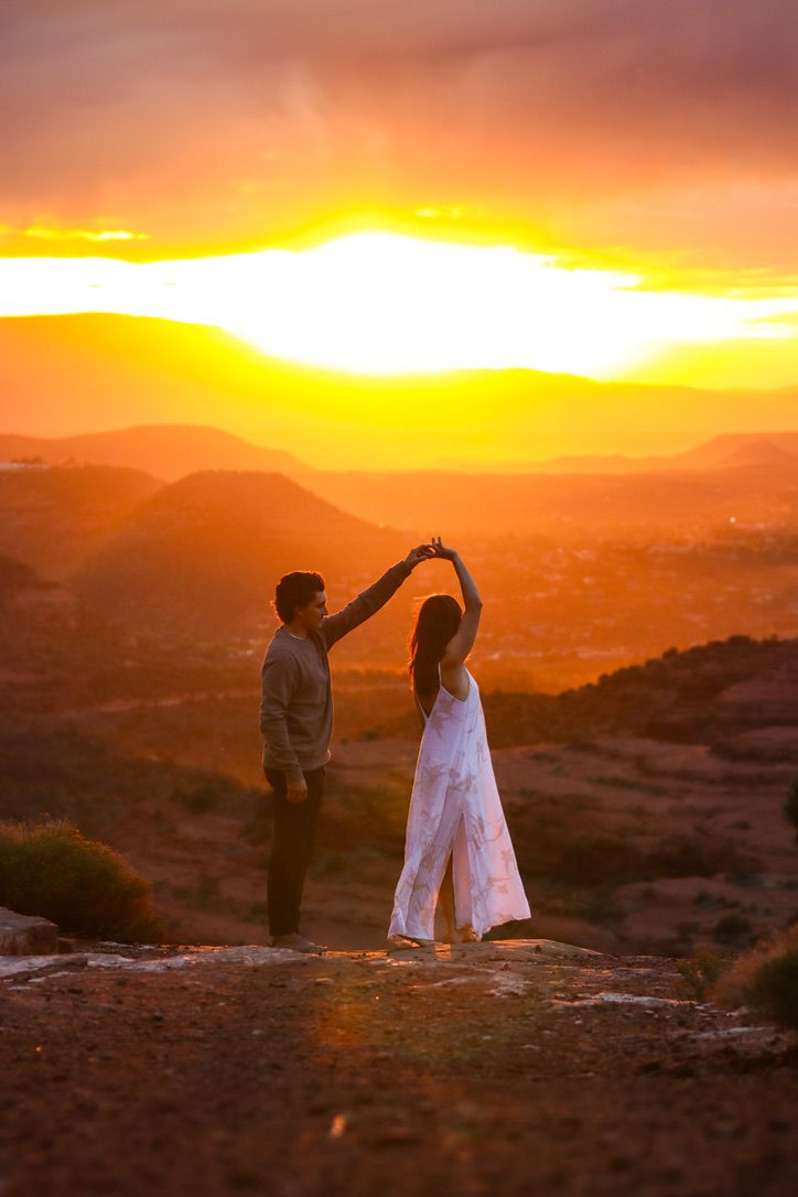 A couple dances together on a cliff edge during a vibrant desert sunset in Sedona Arizona.
