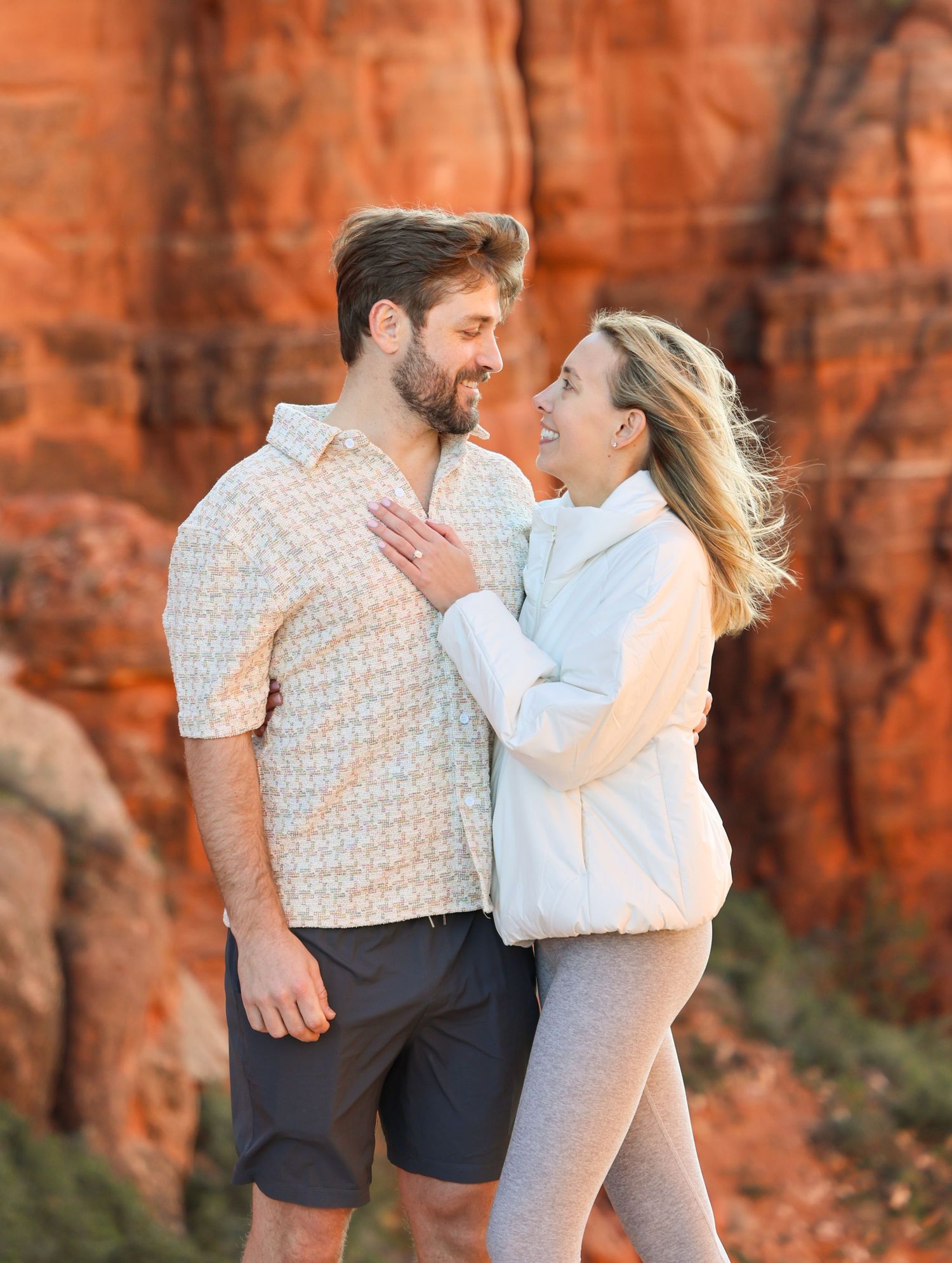 Couple sharing an intimate moment against towering red rock cliffs in Sedona Arizona.