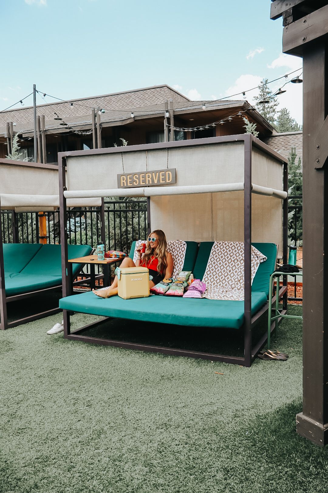 Reserved outdoor seating area with turquoise cushioned daybed and decorative pillows on patio.