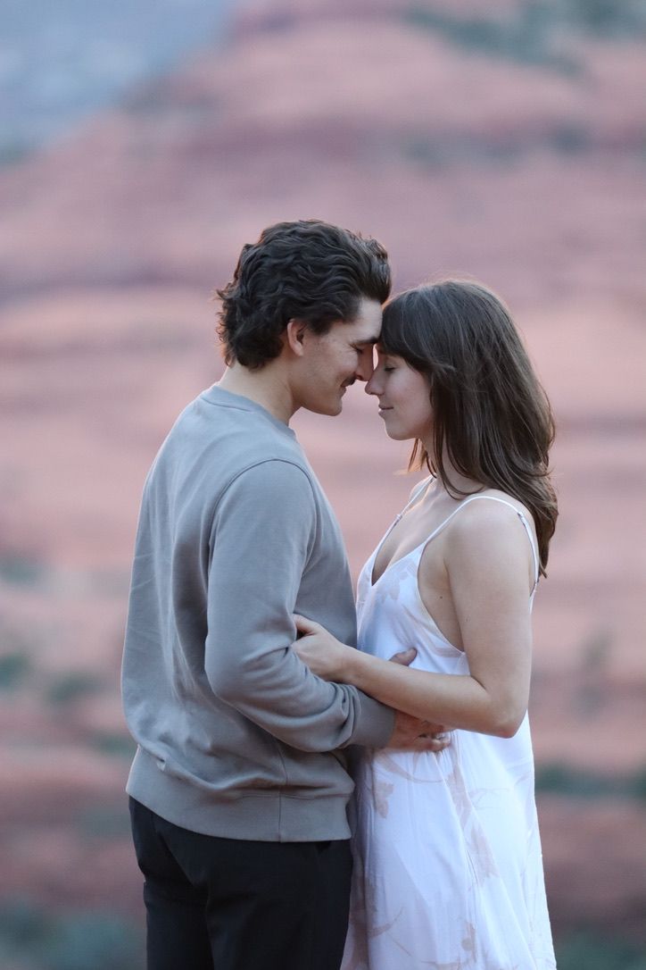 A tender moment between a couple against a backdrop of red desert cliffs in Sedona Arizona.