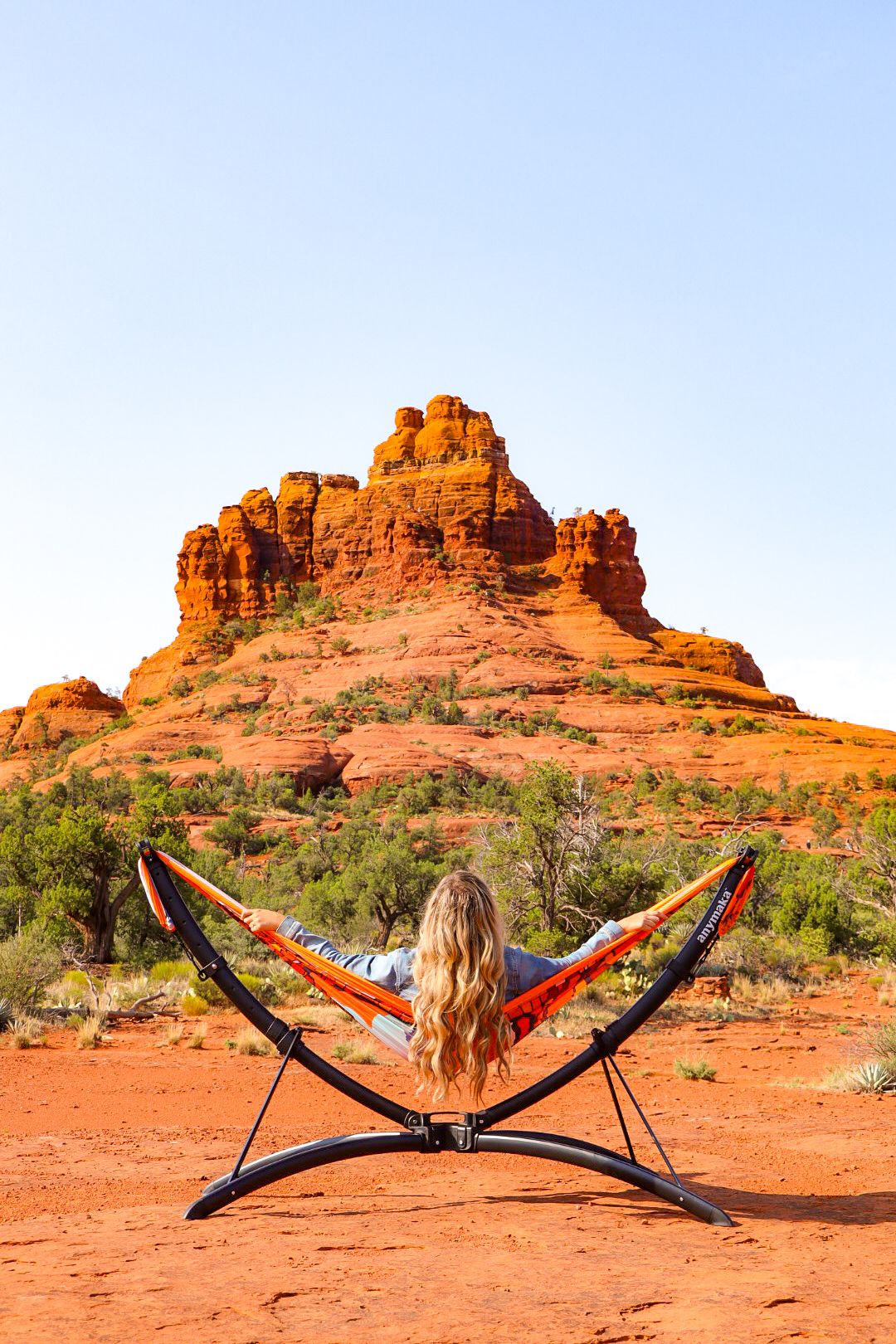 Someone relaxes in a hammock against stunning red rock formations at Bell Rock in Sedona, Arizona.